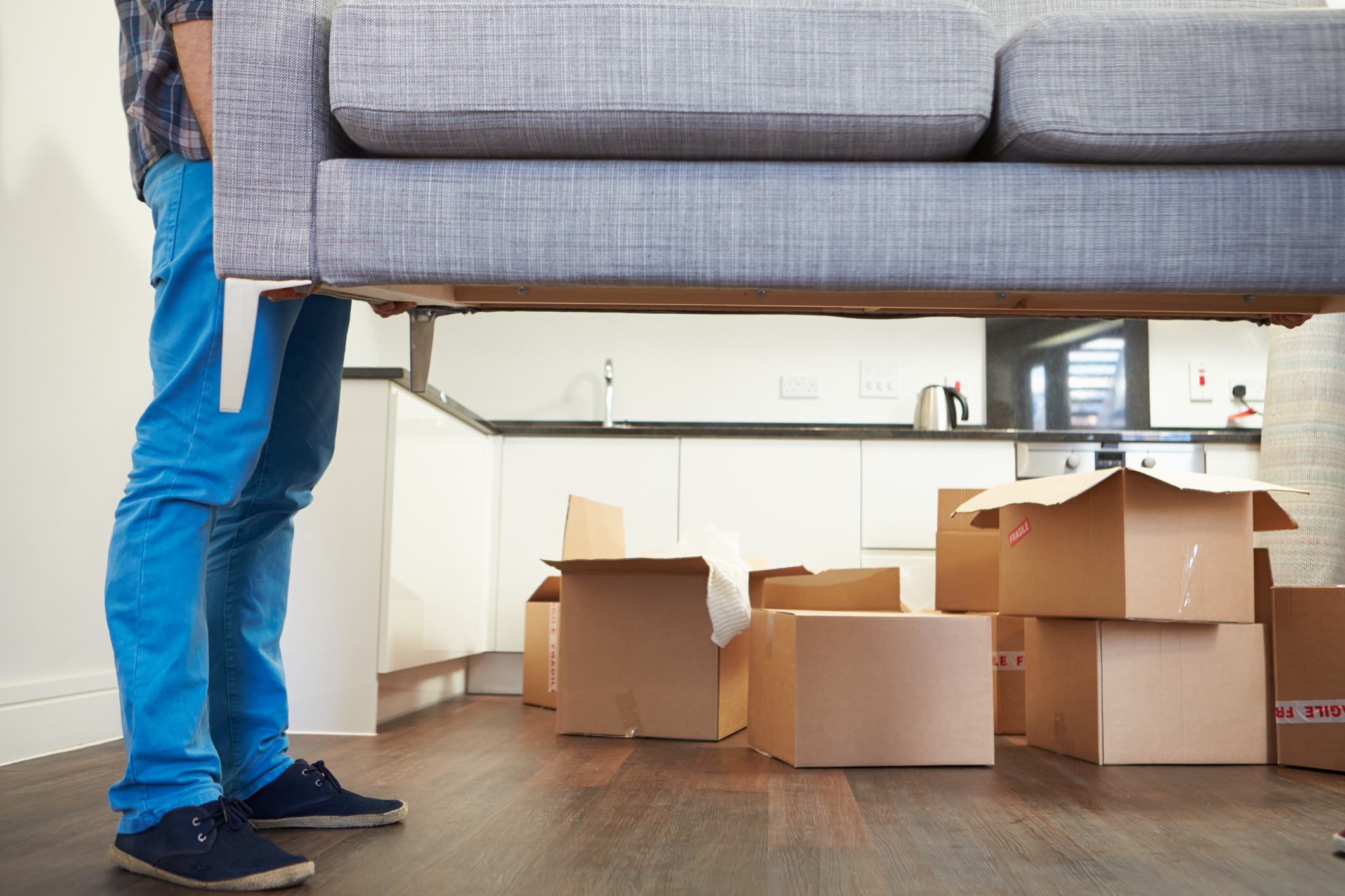 Umzug & Jobcenter: Kosten, Anträge & Begründungen mit Bürgergeld Umzugshelfer tragen Sofa aus der Wohnung im Hintergrund stehen Umzugskartons