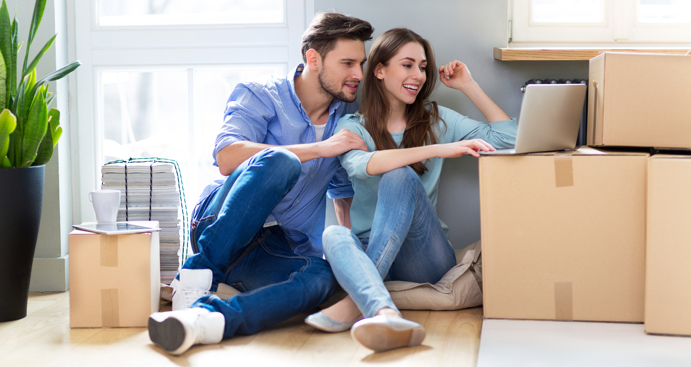 GEZ ummelden: So funktioniert es Paar sitzt mit Laptop zwischen Umzugskisten