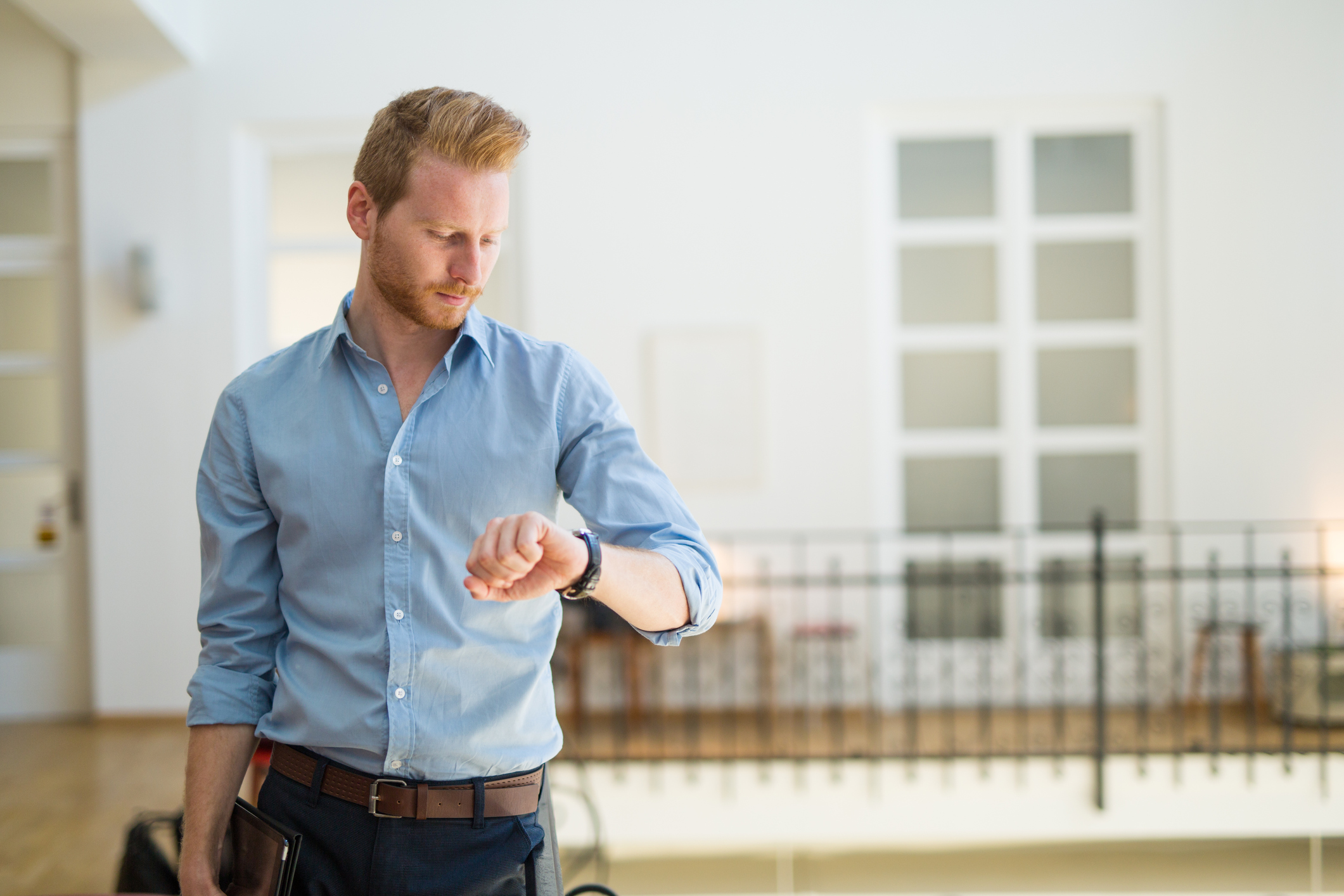 Wohnungsübergabe ohne Vermieter: Was Sie darüber wissen sollten Junger Mann schaut auf seine Armbanduhr