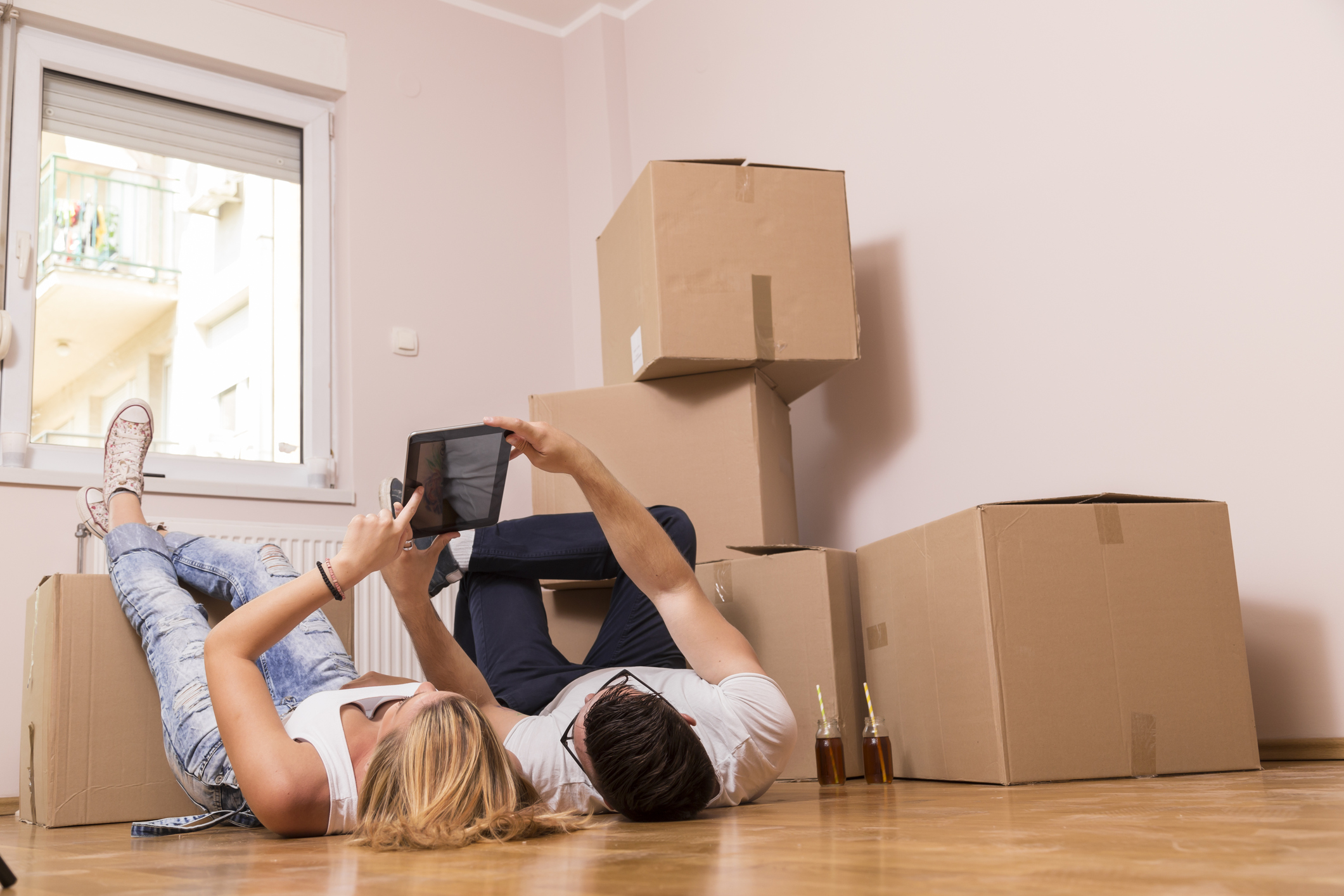 Pärchen liegt vor Umzugskisten und schaut auf Table