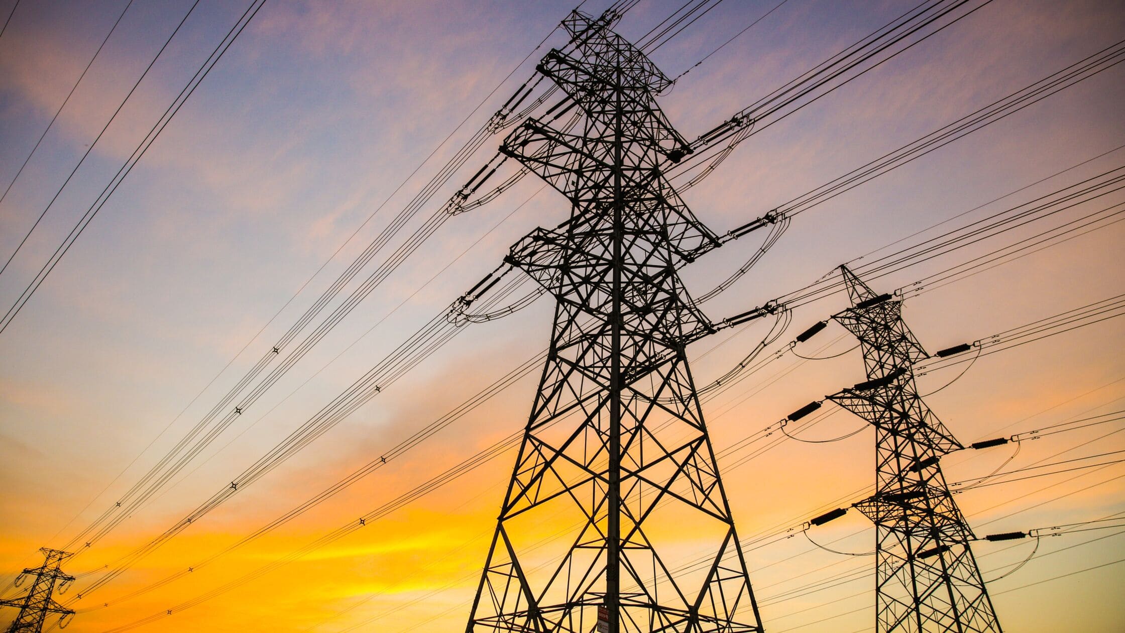 Strommast vor orangefarbenem Himmel