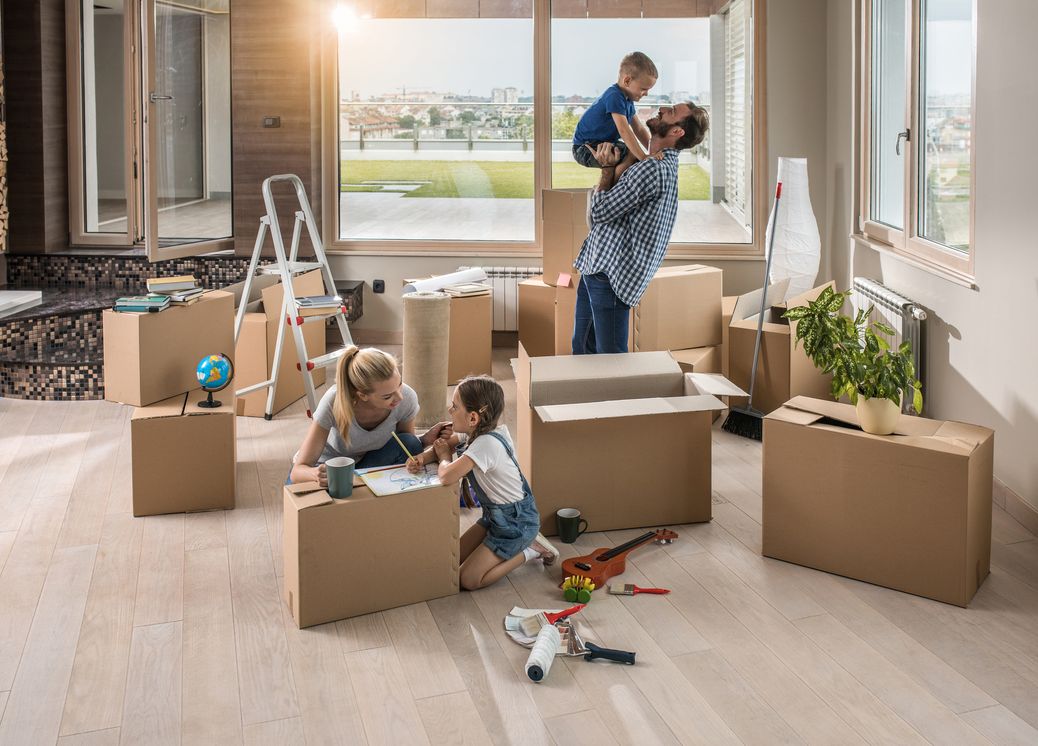 Eltern und zwei Kinder zwischen Umzugskisten im Wohnzimmer.