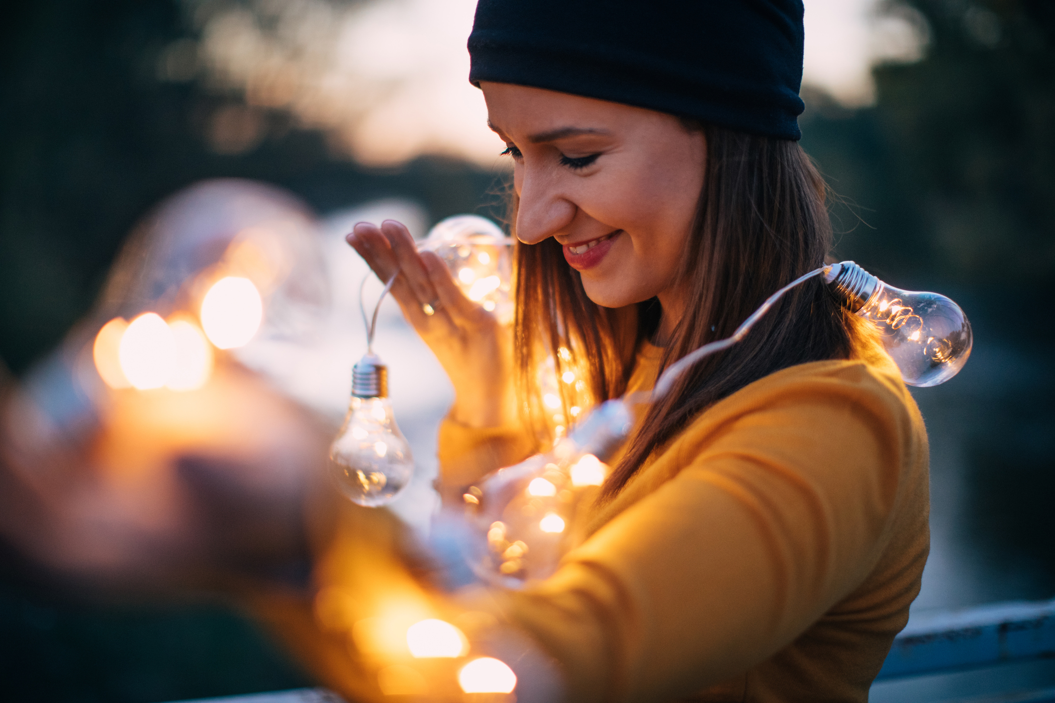 Junge Frau draußen mit leuchtenden Glühlampen.