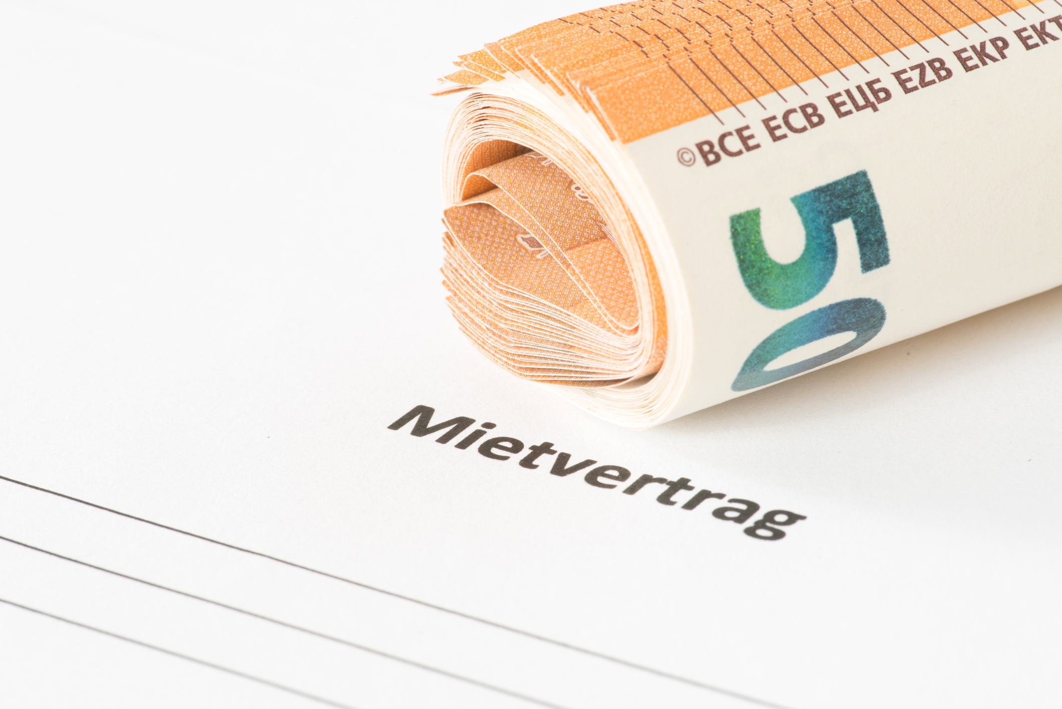 Rückzahlung der Mietkaution: Fristen & Regeln für die Auszahlung Zusammengerollte Geldscheine liegen auf einem Mietvertrag