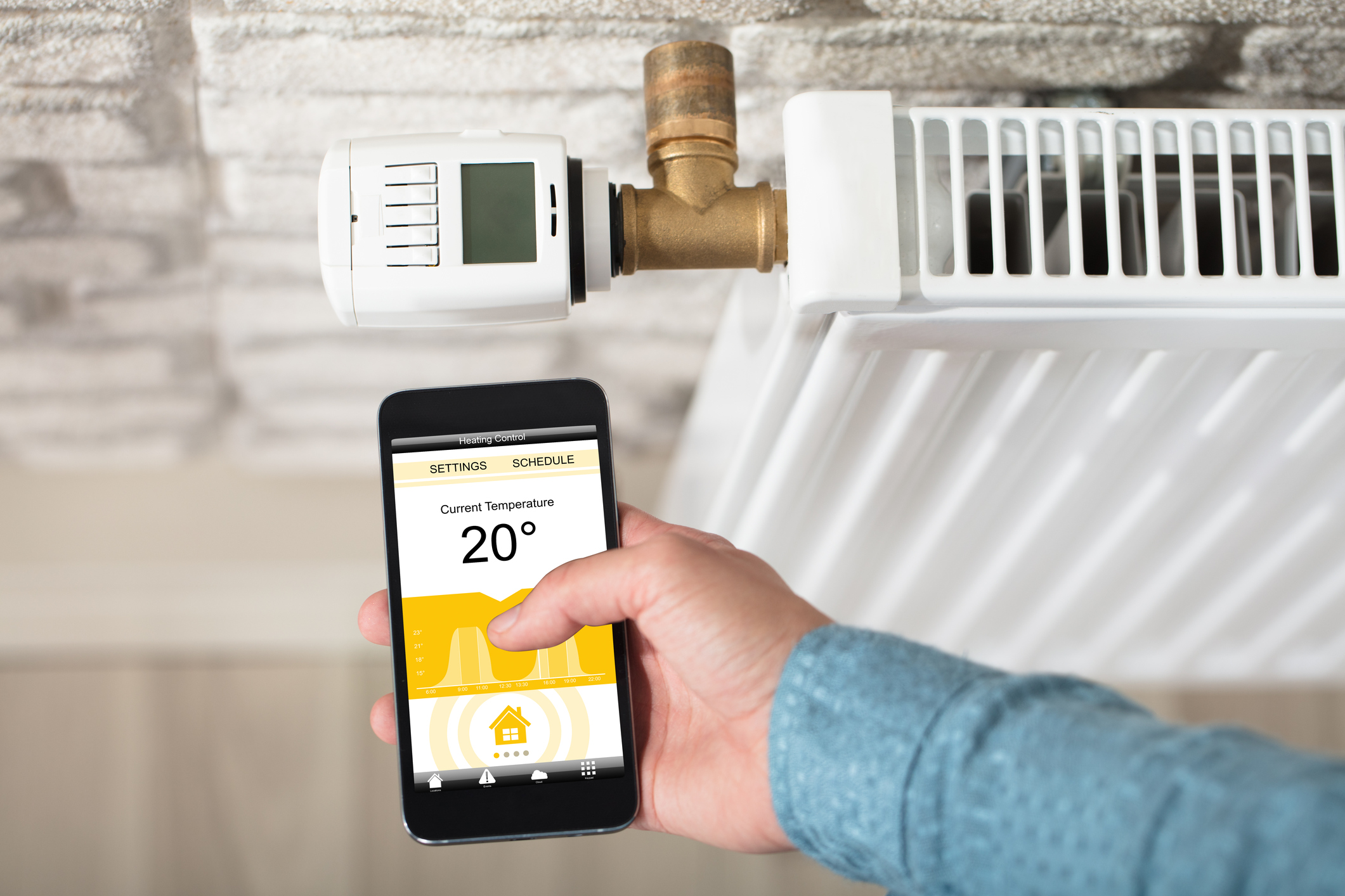 Person misst Raumtemperatur mit Smartphone, im Hintergrund ein Heizkörper