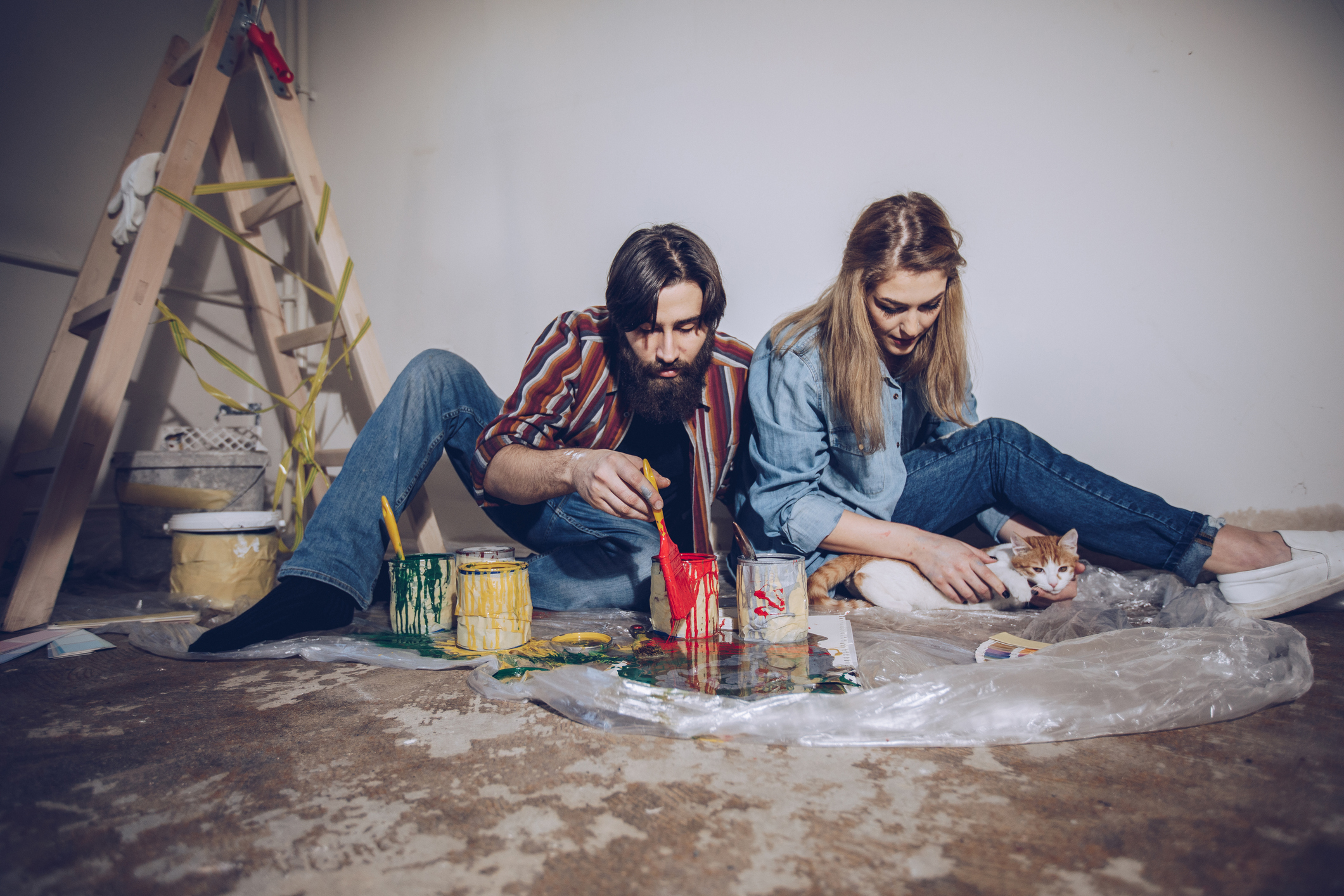 Umzug mit Katze: Tipps für Freigänger & Stubentiger Junges Paar renoviert und spielt mit der Katze.