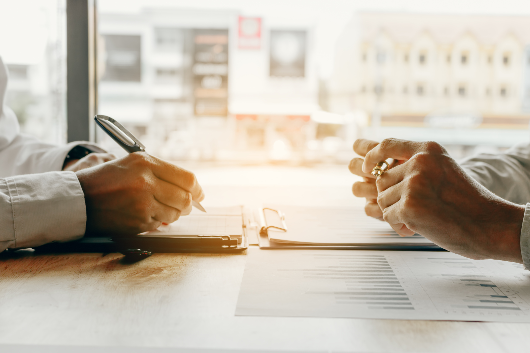 Mietkaution anlegen: 6 Optionen und deren Zinsenabout budget company in office room. Zwei Paar Hände, Close-up, mit Stiften und Unterlagen
