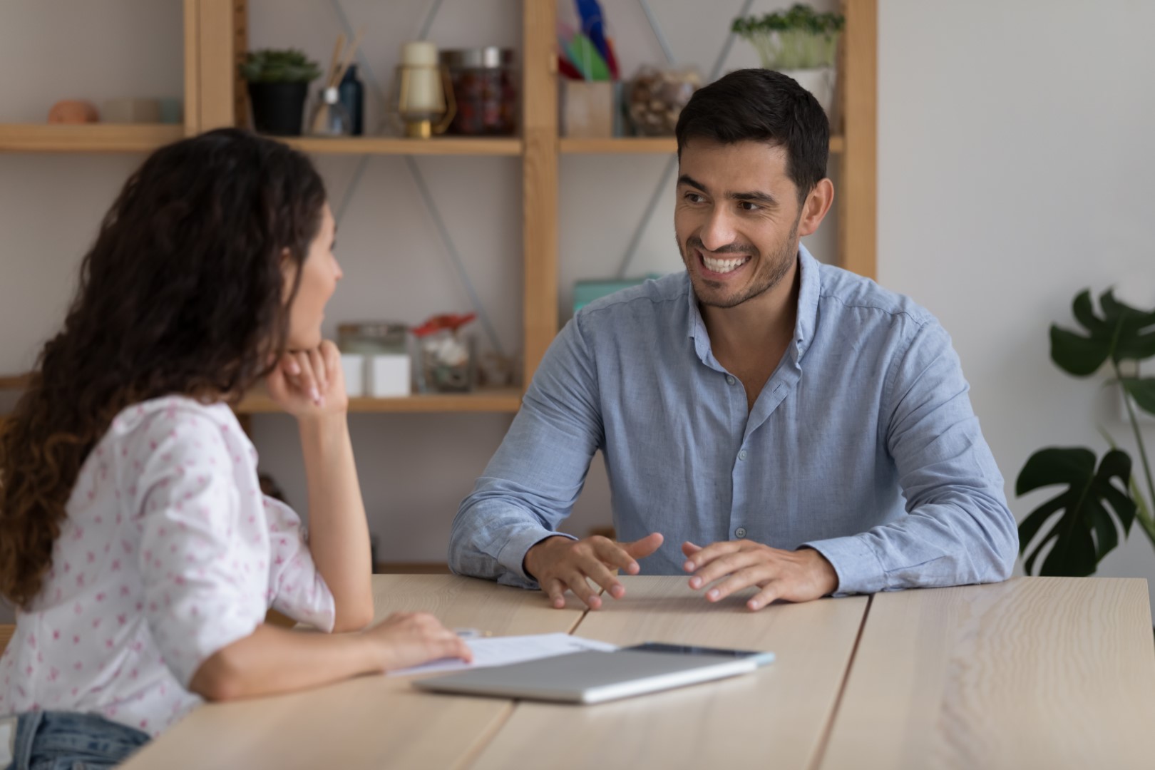 Wohnungssuche für Flüchtlinge: Tipps und Hilfen für den Weg zur eigenen Wohnung Junger Mann am Tisch im Gespräch mit junger Frau, davor Tablet, Smartphone und Notizzettel.
