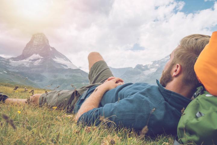 Wanderer liegt auf Bergwiese und schaut aufs Matterhorn