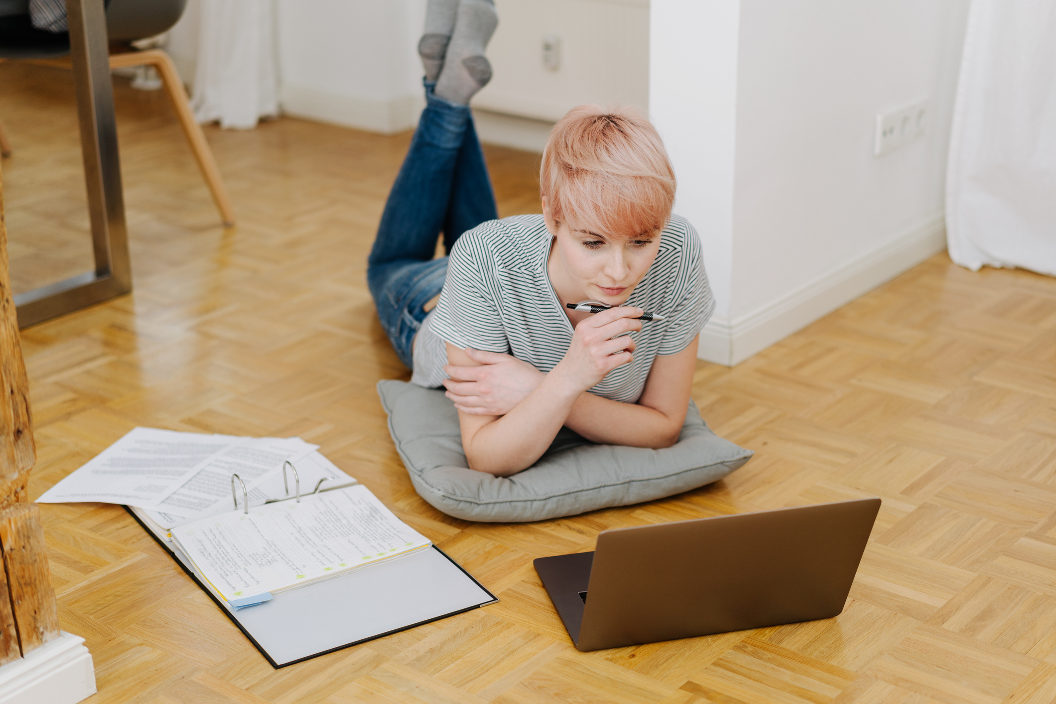 Frau arbeitet am Boden an Computer und Dokumenten.