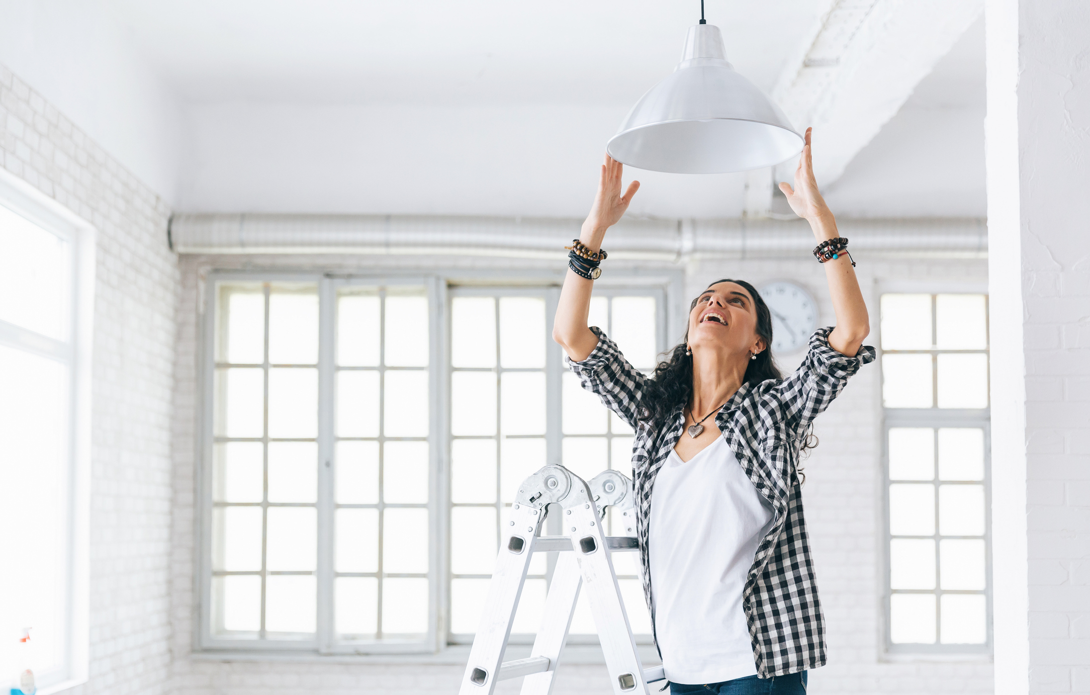 Lampen anbringen leicht gemacht: Tipps für die schnelle Montage Frau hängt Lampe auf