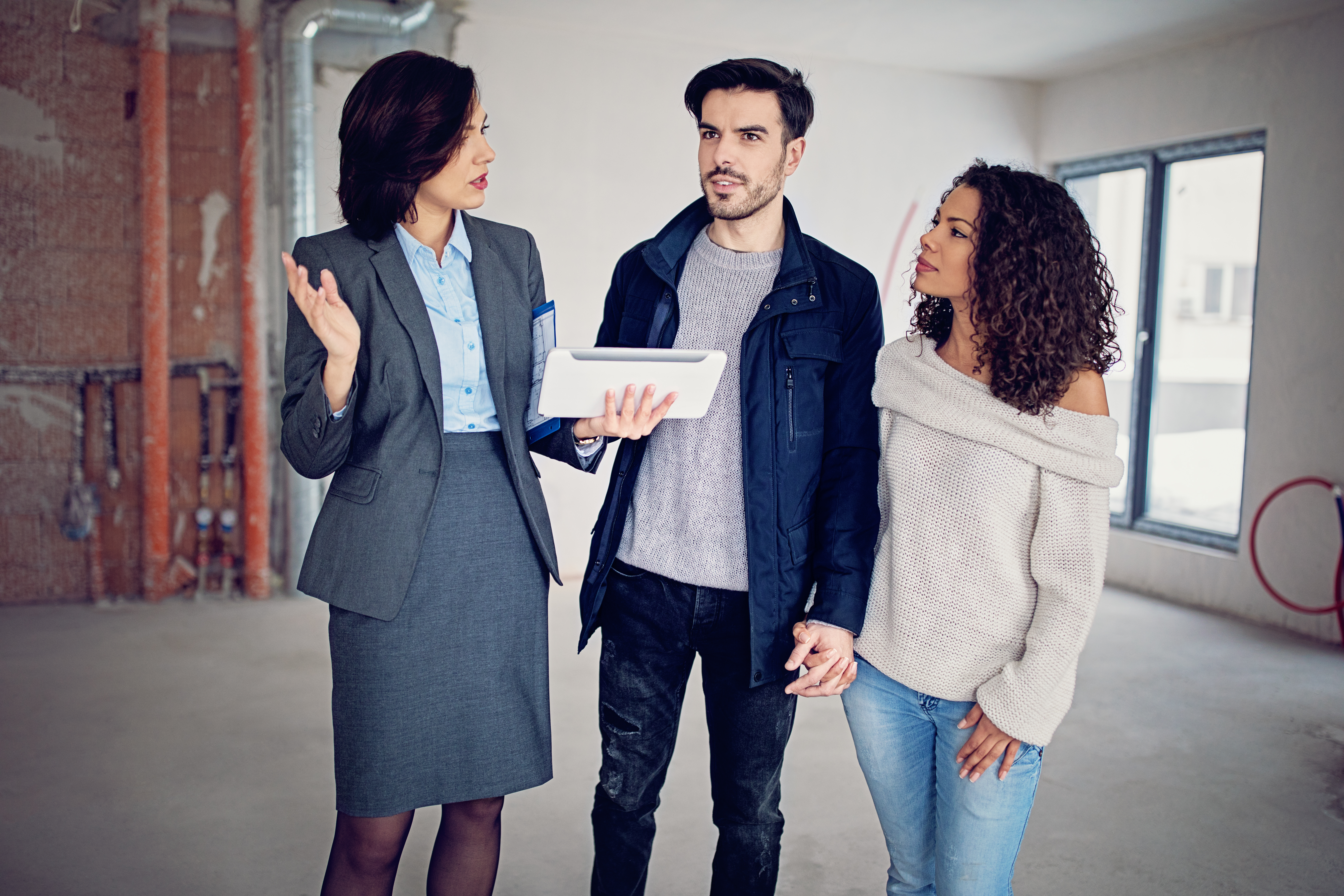 Maklerprovision beim Hauskauf: Wer zahlt die Maklergebühr? Junges Paar mit Maklerin beim Hauskauf