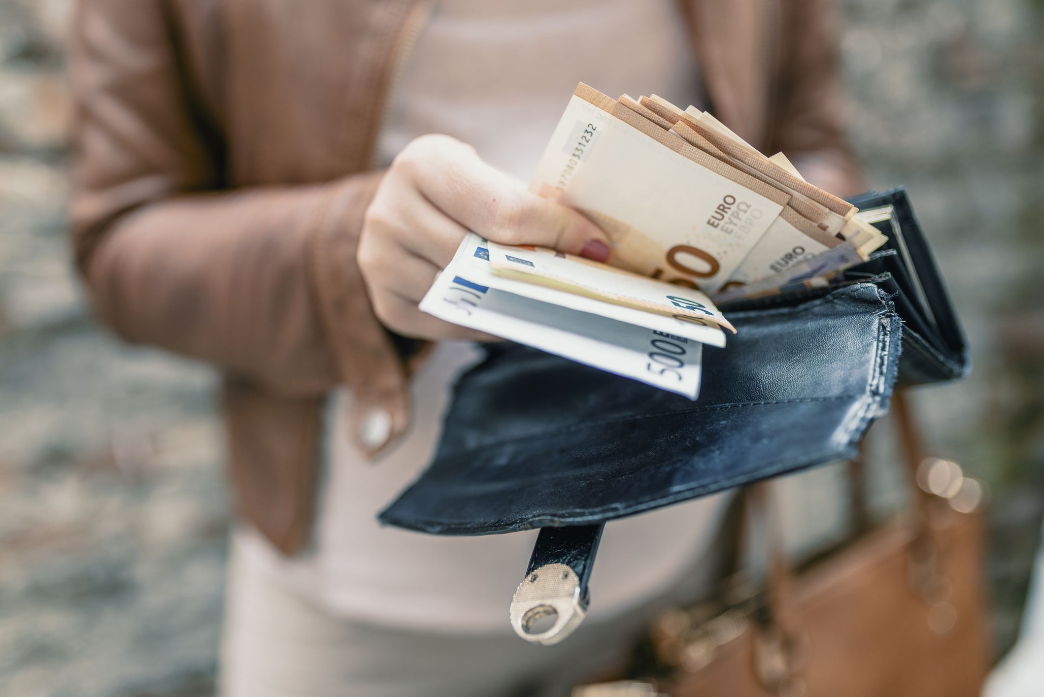 Maklerprovision bei Miete: Was zahlen Mieter und Vermieter? Frauenhand nimmt ein Bündel Geldscheine aus einem Geldbeutel
