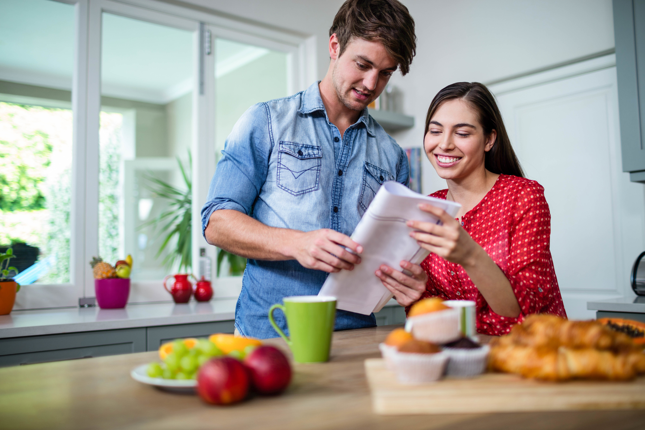 Happy couple having breakfast and reading newspaper at home
