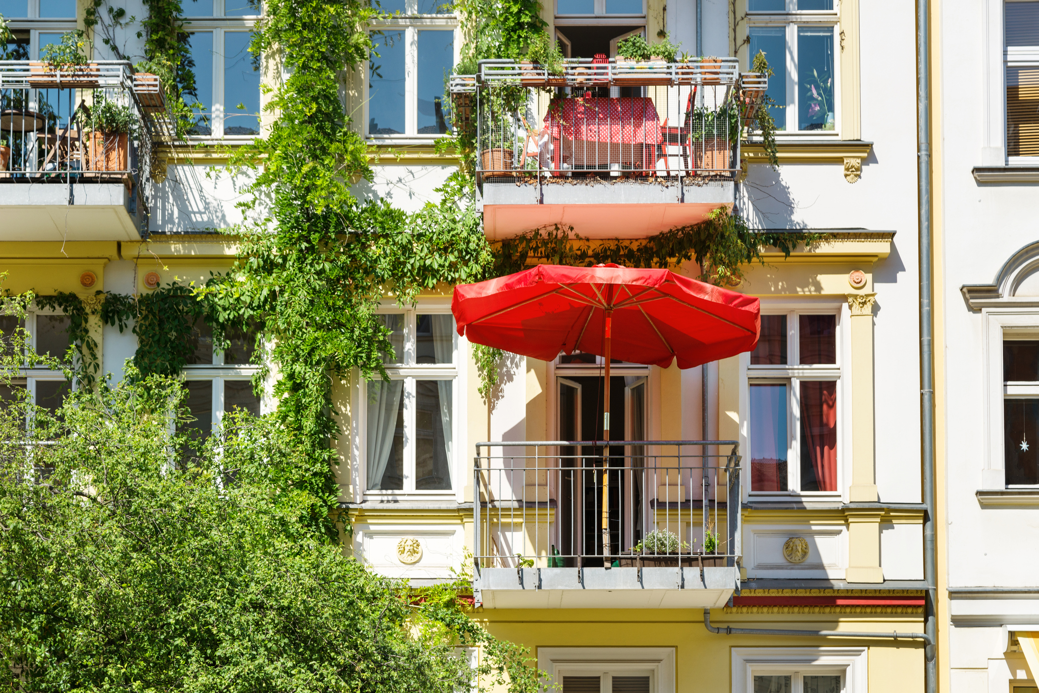 Mieterrechte und Mieterpflichten: Do & Don Außenansicht eines größeren Mietshauses mit bepflanzten Balkons und Sonnenschirm