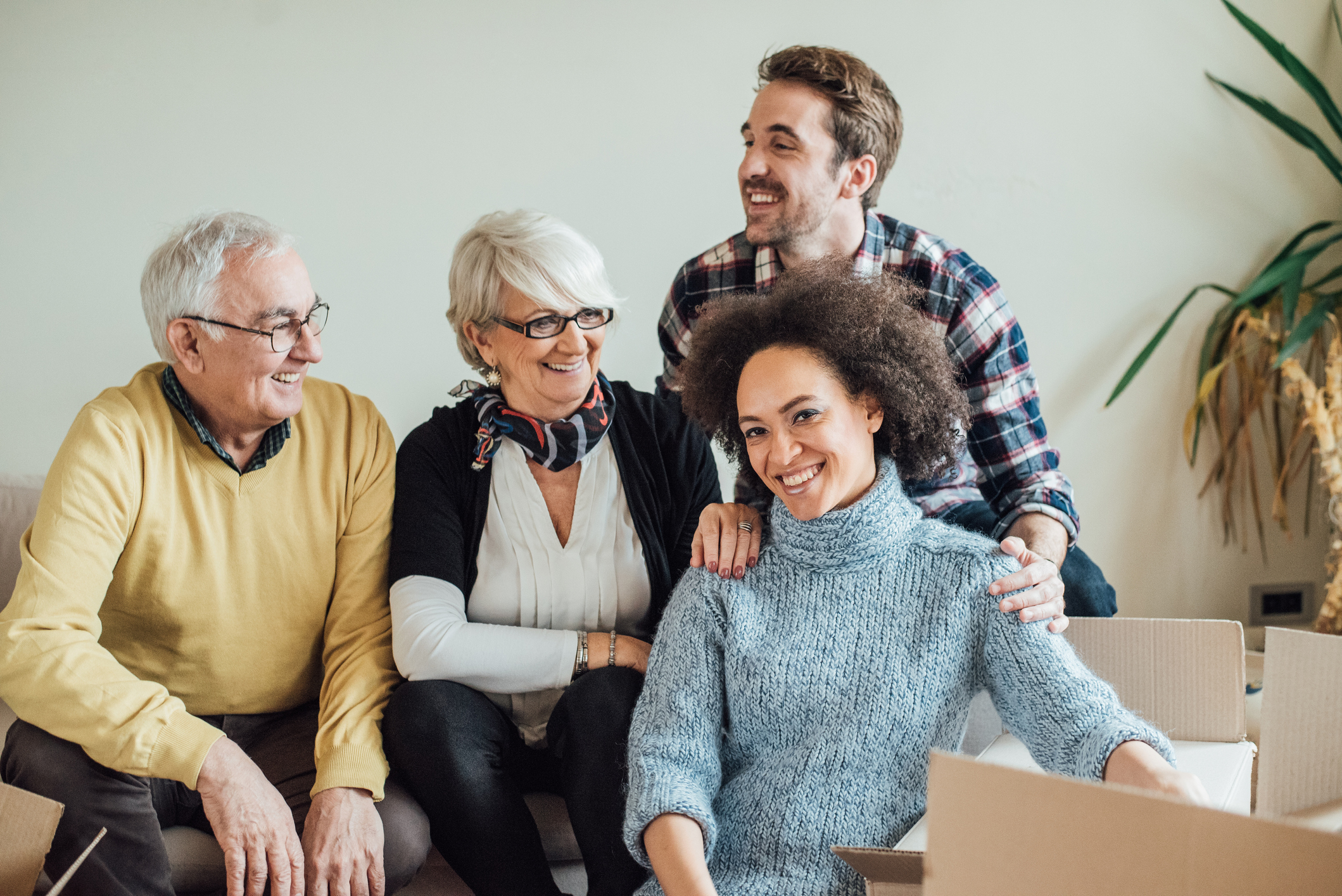 Junges Paar sitzt glücklich mit Eltern in neuer Wohnung
