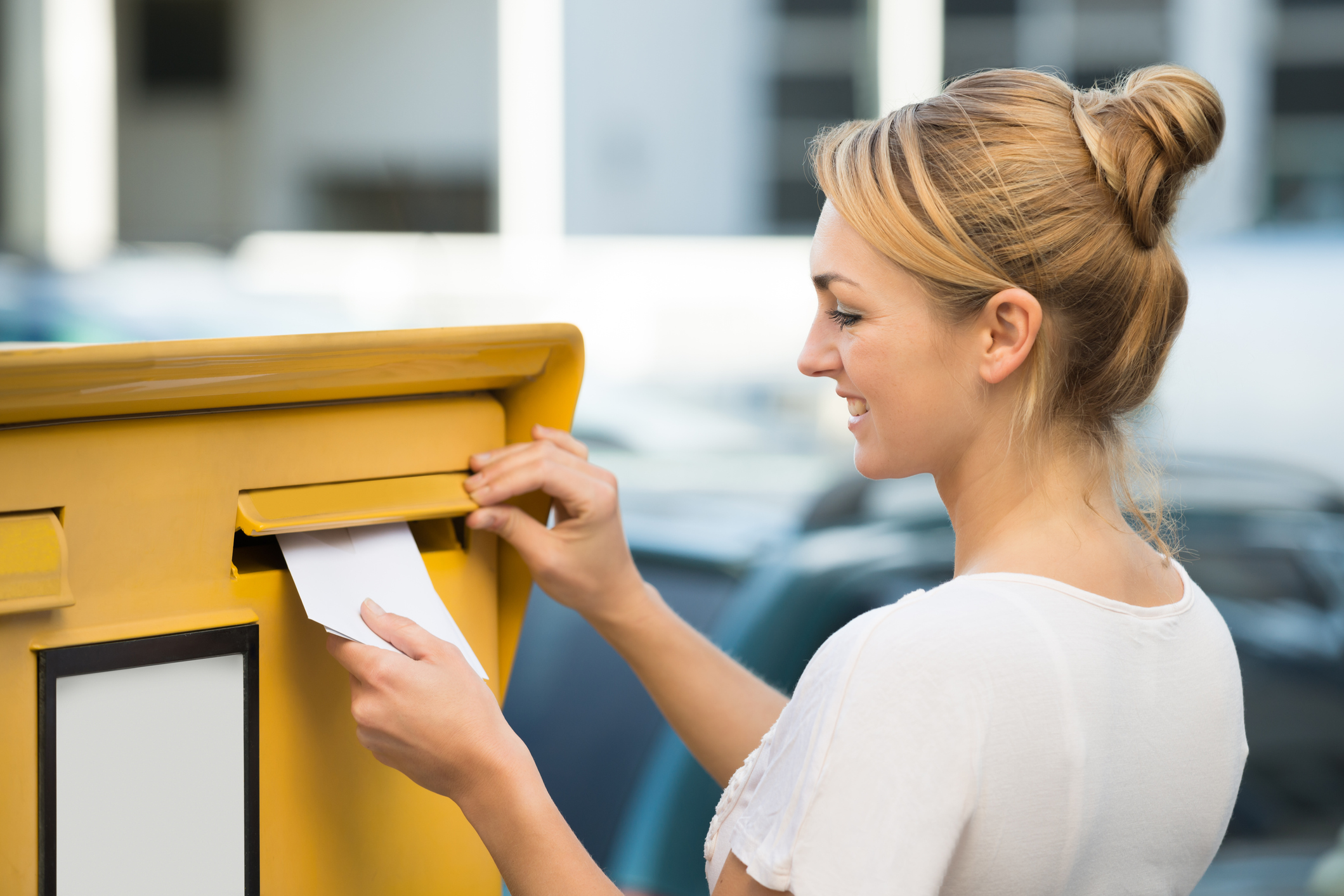 Kündigung des Mietvertrages: Fristen, Muster und Tipps Junge Frau steckt Kündigung des Mietvertrages in den Postkasten.