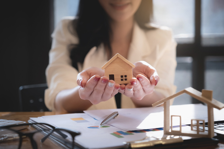 Hausverwaltung: Dafür ist sie da Frau hält kleines Haus schützend in den Händen