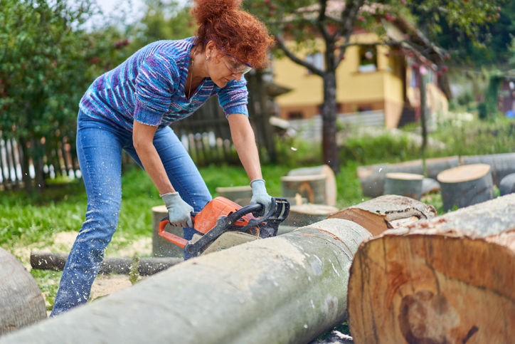 Wohnung mit Garten mieten: Welche Rechte und Pflichten habe ich?_Baum fällen Frau fällt einen Baum mit Kettensäge