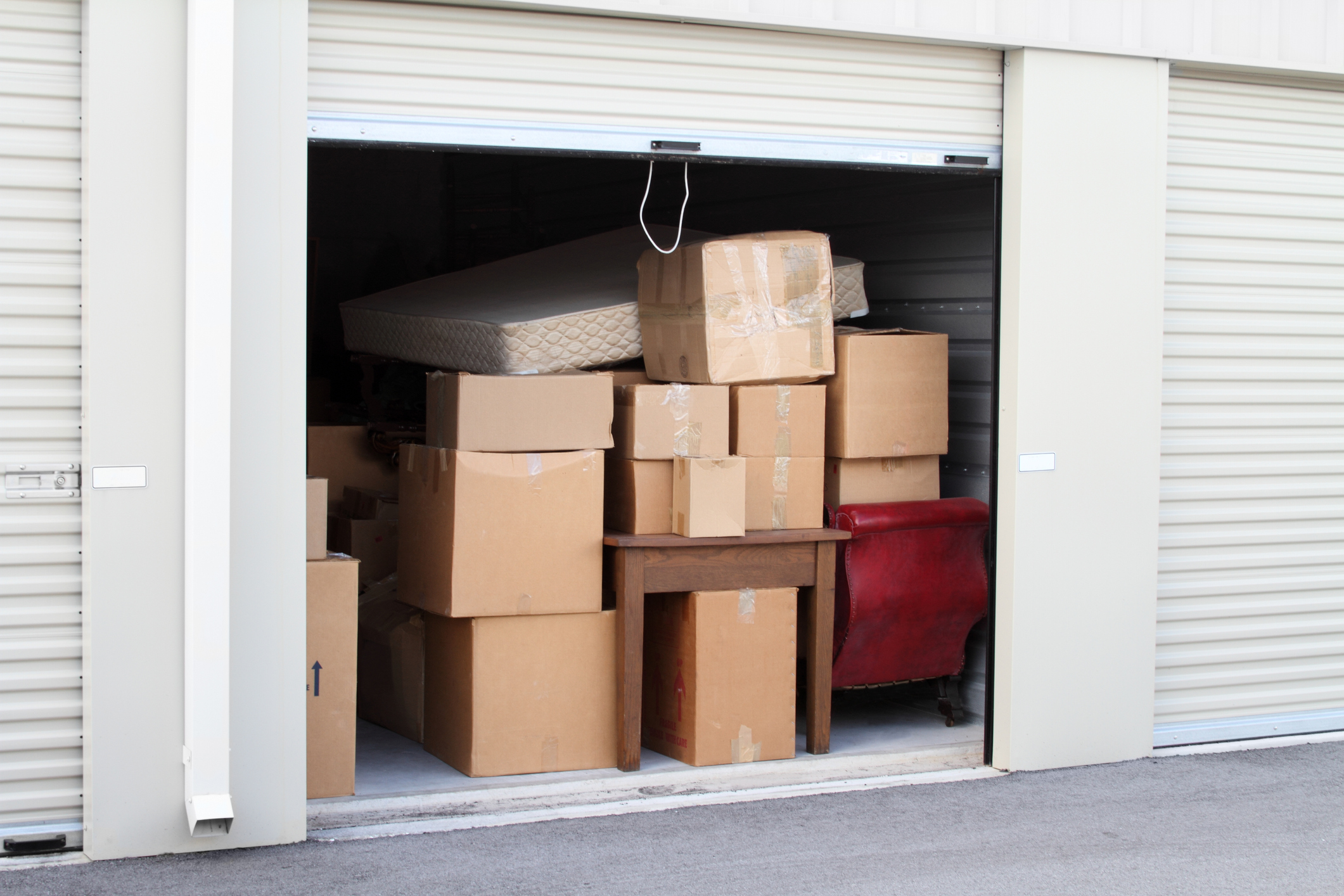 Möbel einlagern: Tipps für Selfstorage beim Umzug Eingelagerte Möbel und Kartons stehen in einem Selfstorage-Abteil