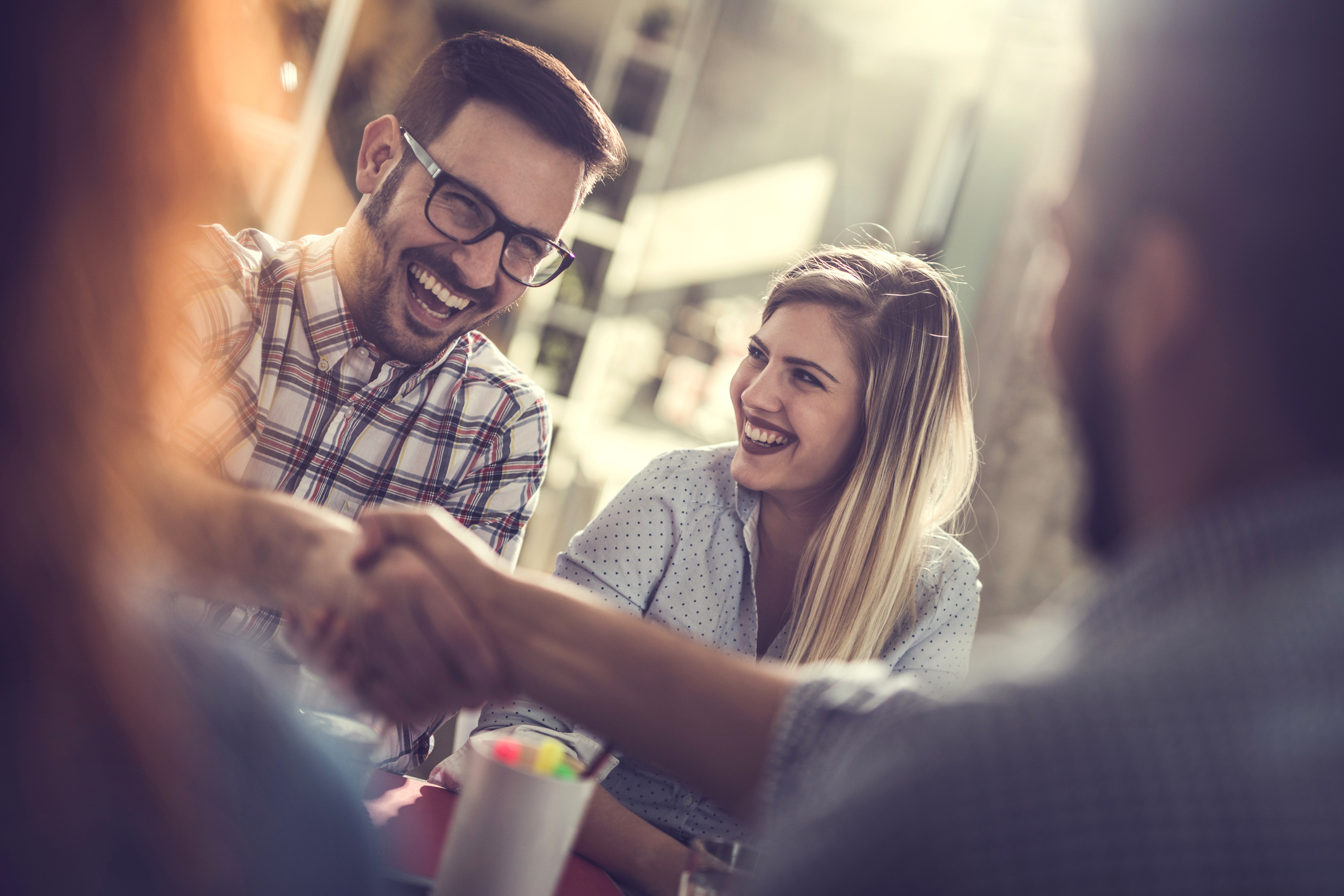 Junger Mann schüttelt einem anderen Mann lachend die Hand