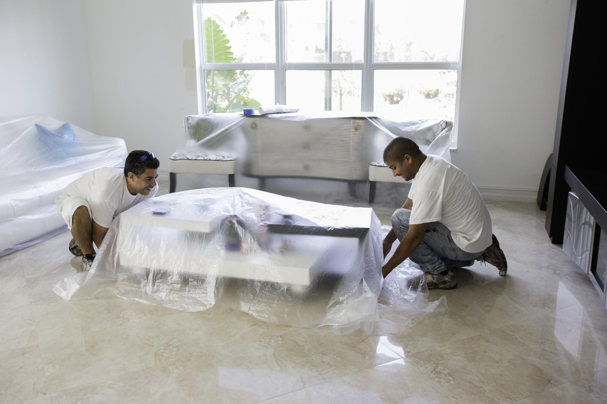 Selber richtig tapezieren: Anleitung für Anfänger Männer decken Möbel mit Folie ab