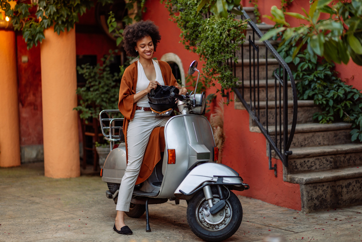 Roller transportieren Frau sitzt auf Motorroller und hält Helm in der Hand