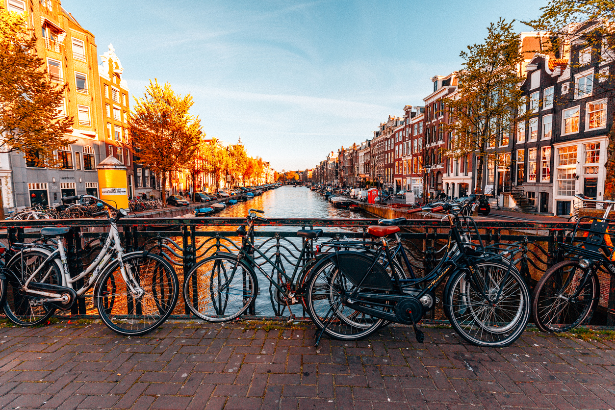 Auswandern in die Niederlande: In Holland heimisch werden Auf einer Brücke über einer Amsterdamer Gracht parken viele Fahrräder