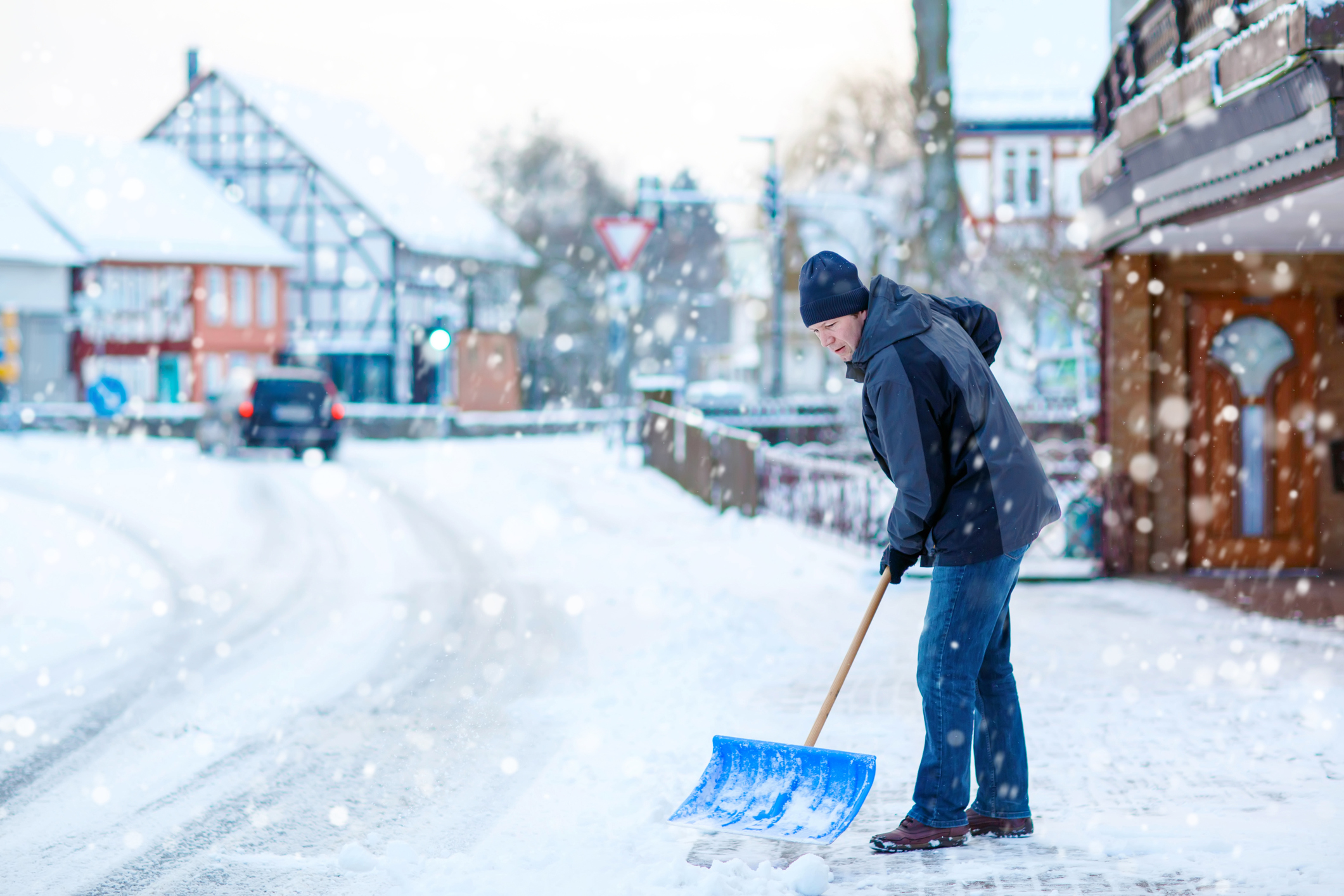 Schneeräumen Pflichten und Informationen Mann räumt Schnee im Winter mit Schaufel