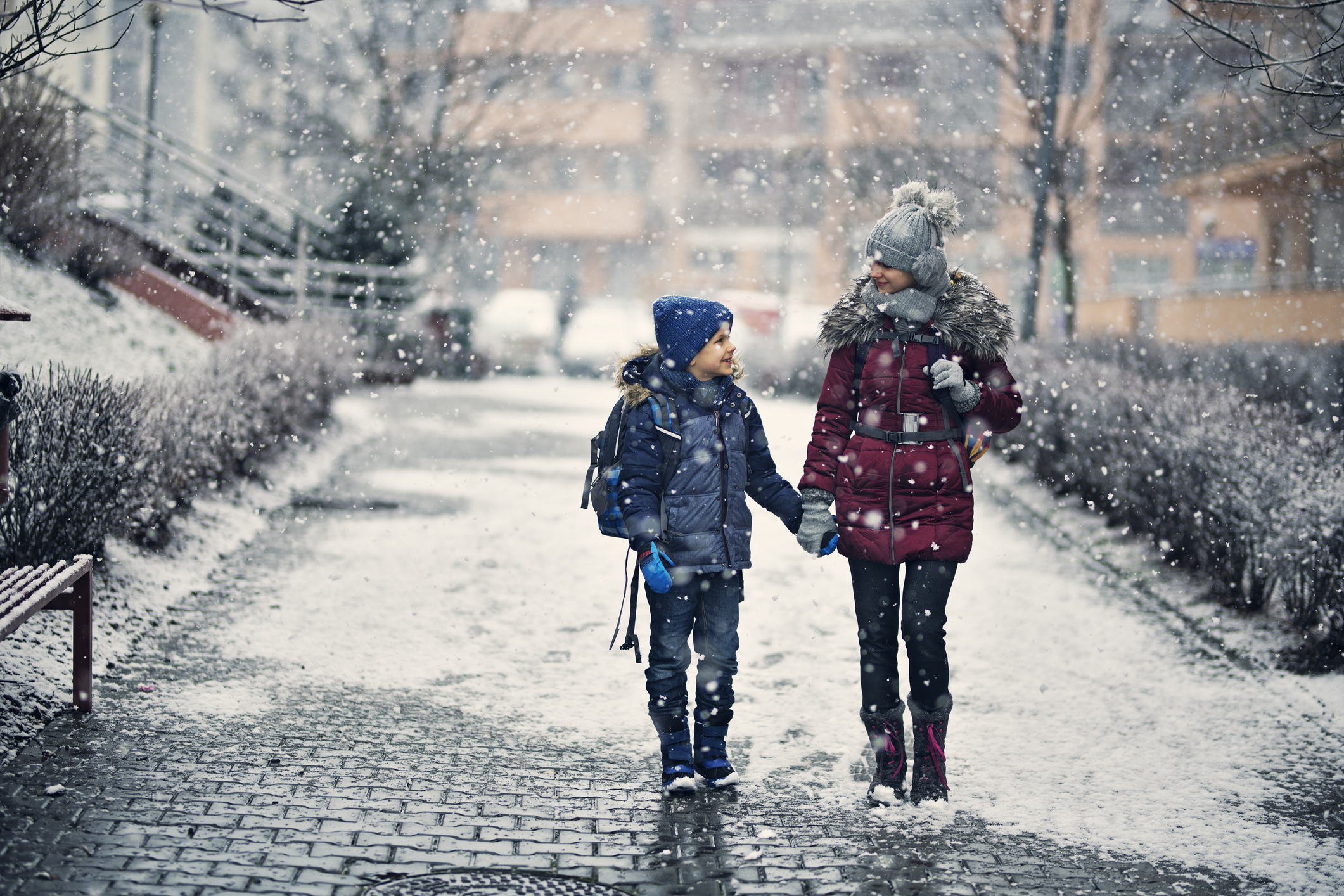 Räum- und Streupflicht: Was Mieter & Vermieter im Winter müssen Geschwisterpaar spaziert im Winter über geräumten Gehweg