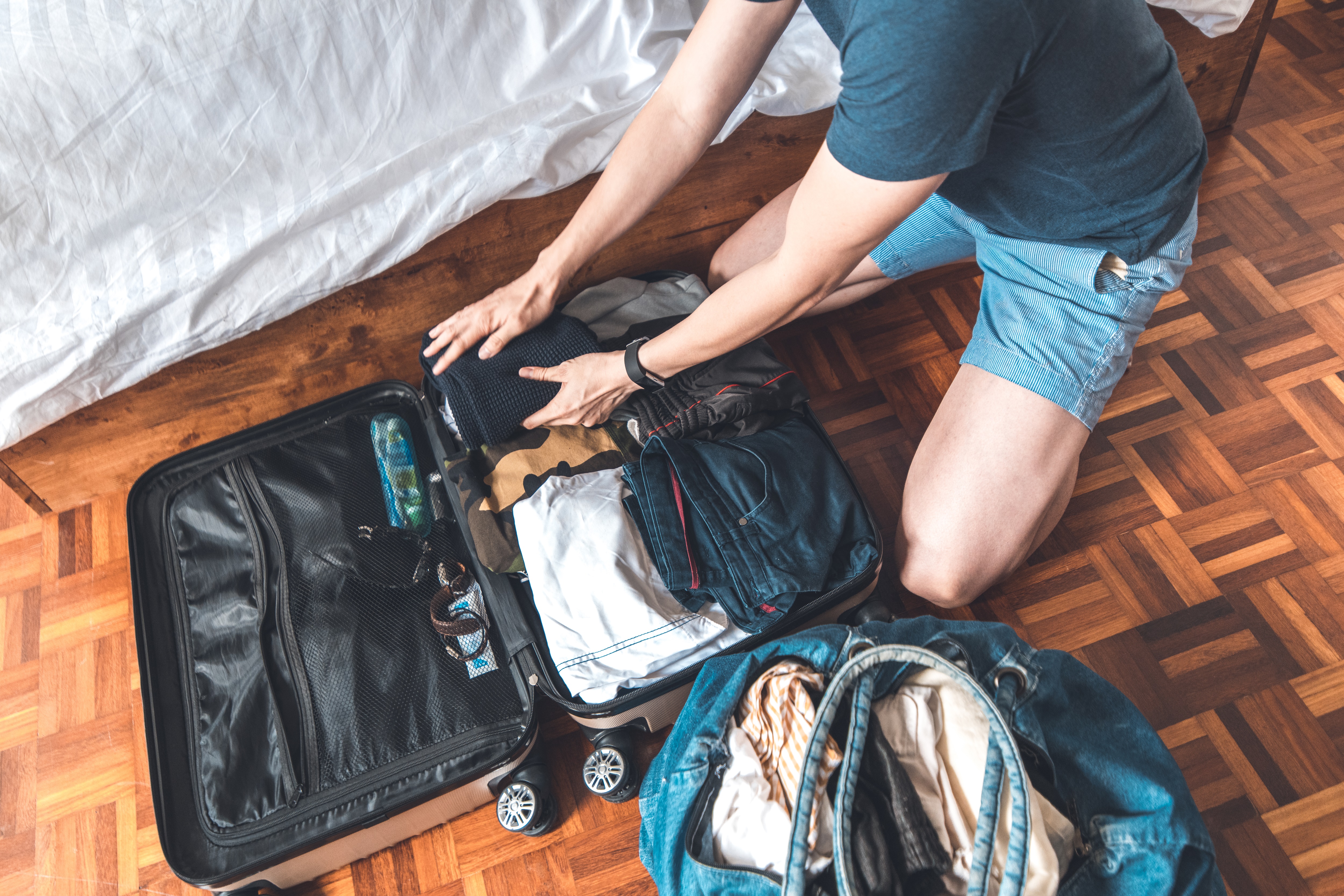 Checkliste für den Umzugstag: Was muss in den Überlebenskoffer? Junger packt einen Koffer