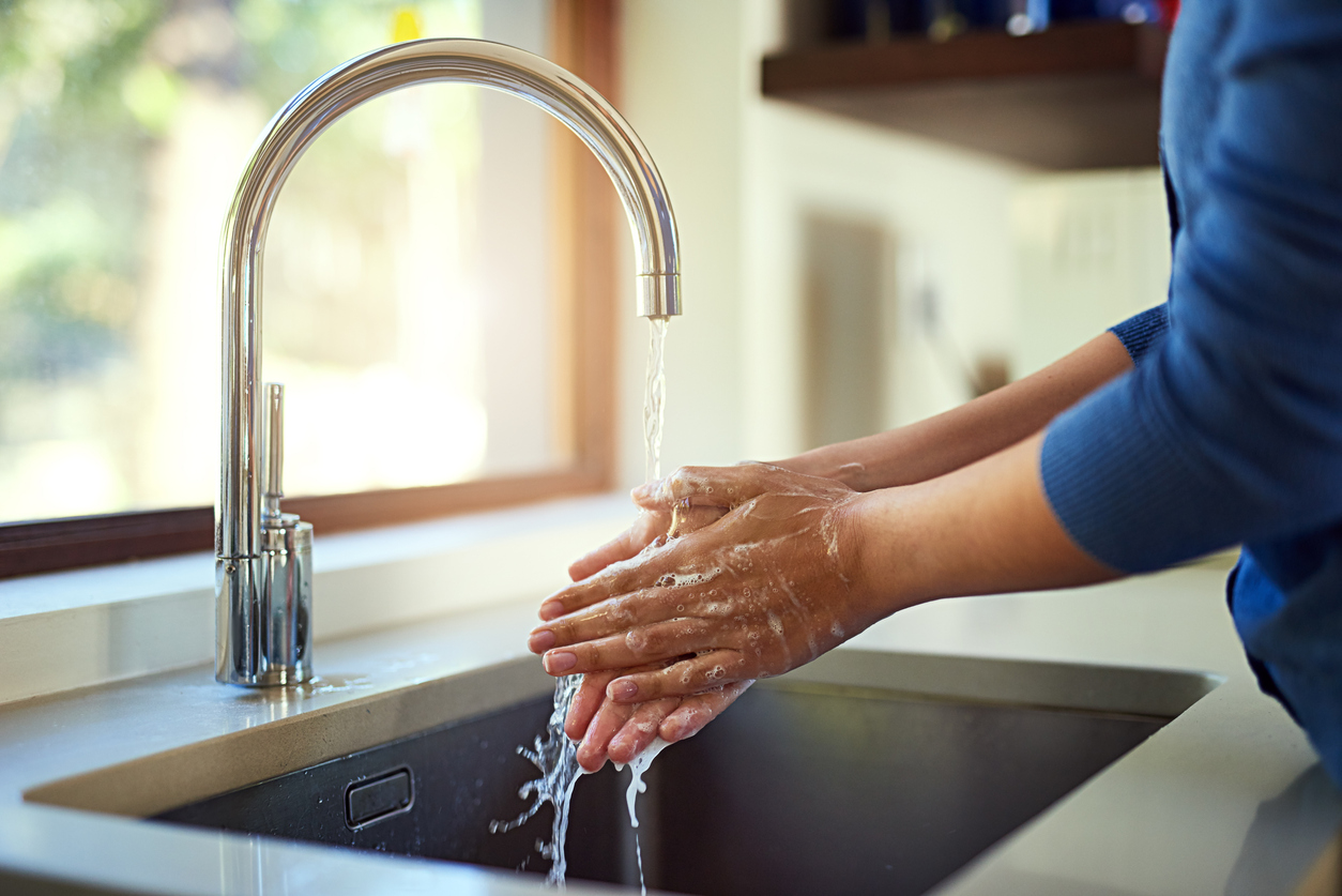 Es kommt zu wenig Wasser aus dem Hahn? Wie Sie den Wasserdruck erhöhen und messen Frau wascht Hände unter Wasserhahn