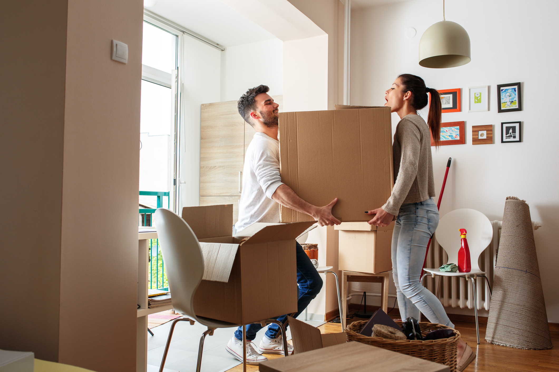 Umzugtipps & Checklisten: So planen Sie Ihren DIY-Umzug Junges Paar schleppt große Kiste zu zweit