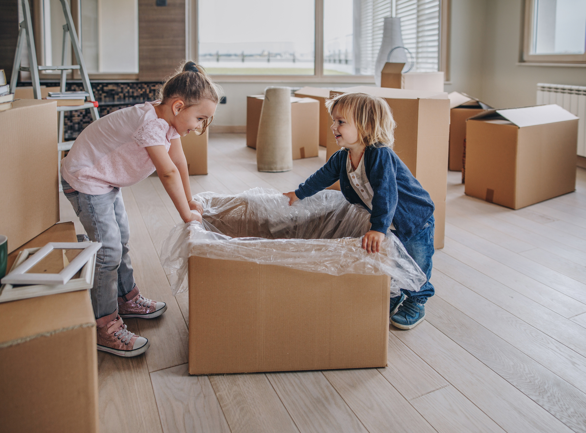 So klappt der Umzug mit Kindern ganz entspannt Mädchen und Junge mit einem Umzugskarton
