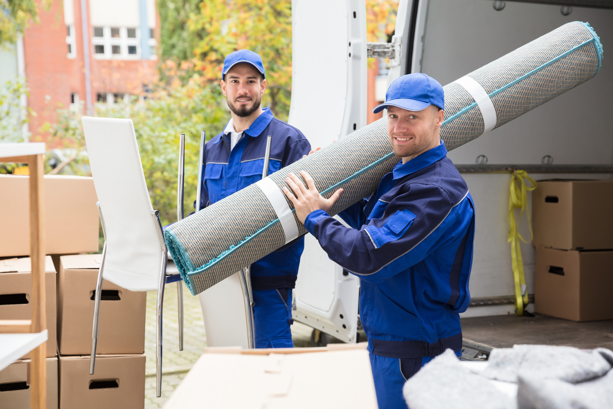 Umzug mit Transportunternehmen: Kosten & Tipps Zwei Möbelpacker laden Umzugsgut aus einem Transporter aus