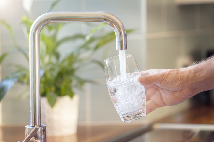 Wasserhärte in der neuen Wohnung messen? Diese Möglichkeiten gibt es Laufender Wasserhahn mit Wasserglas