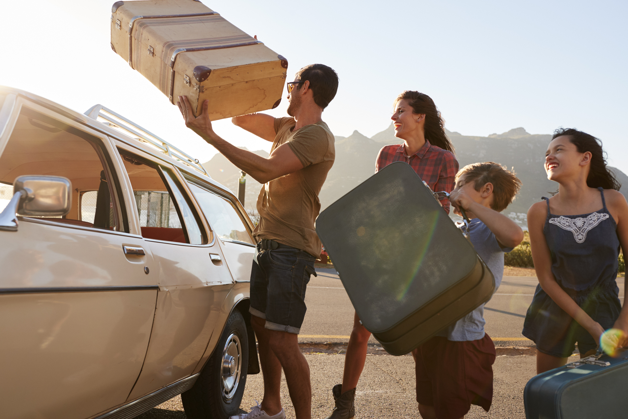 Welche Versicherungen braucht man wirklich? Familie lädt Koffer ins Auto