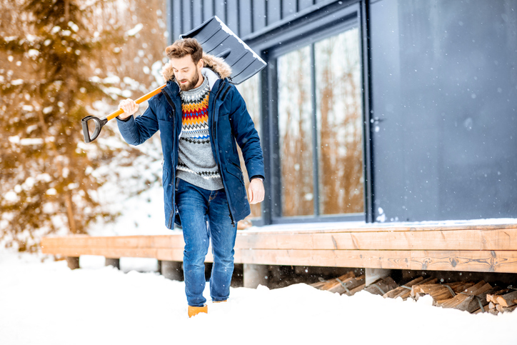 Winterdienst: Das sind Ihre Pflichten als Mieter Mann mit Schneeschaufel geht durch den Schnee