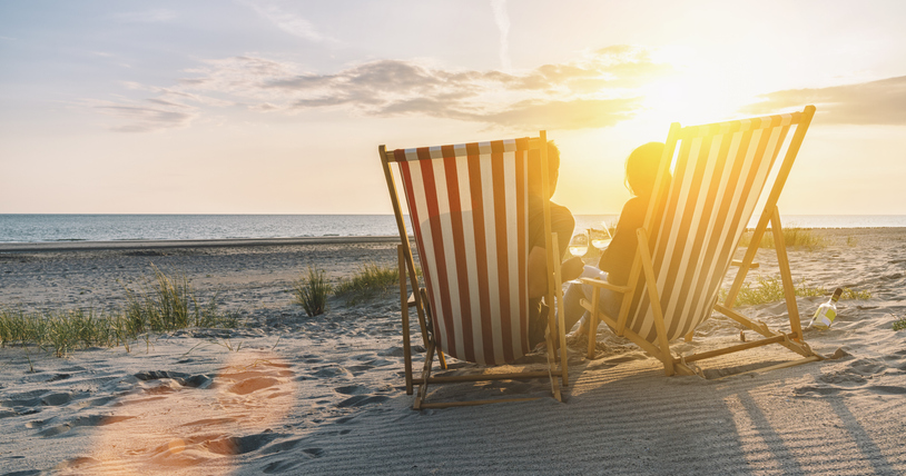 Paar sitzt in Liegestühlen am Strand