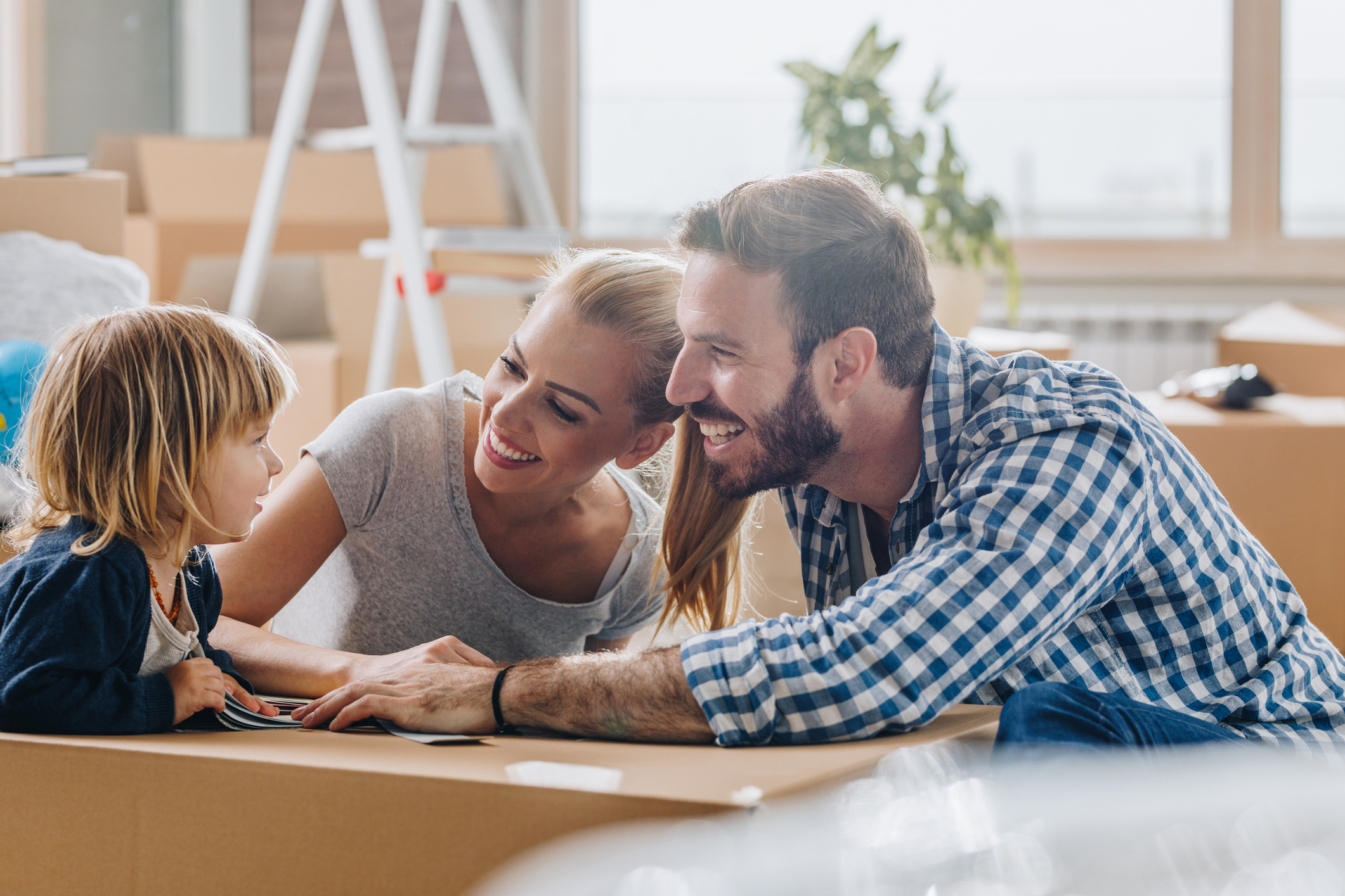 Eltern und Sohn zwischen Umzugskartons in neuer Wohnung
