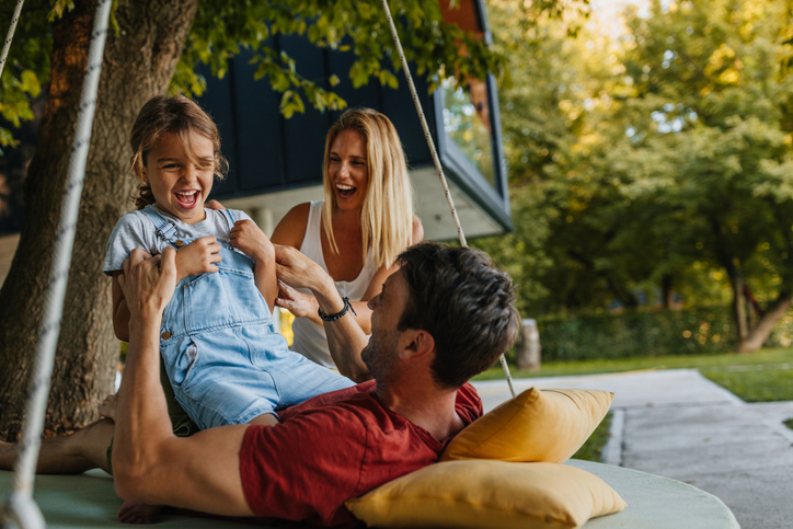 Wohnung mit Garten mieten: Welche Rechte und Pflichten habe ich? Eltern spielen mit ihrem Kind im Garten vor dem Haus