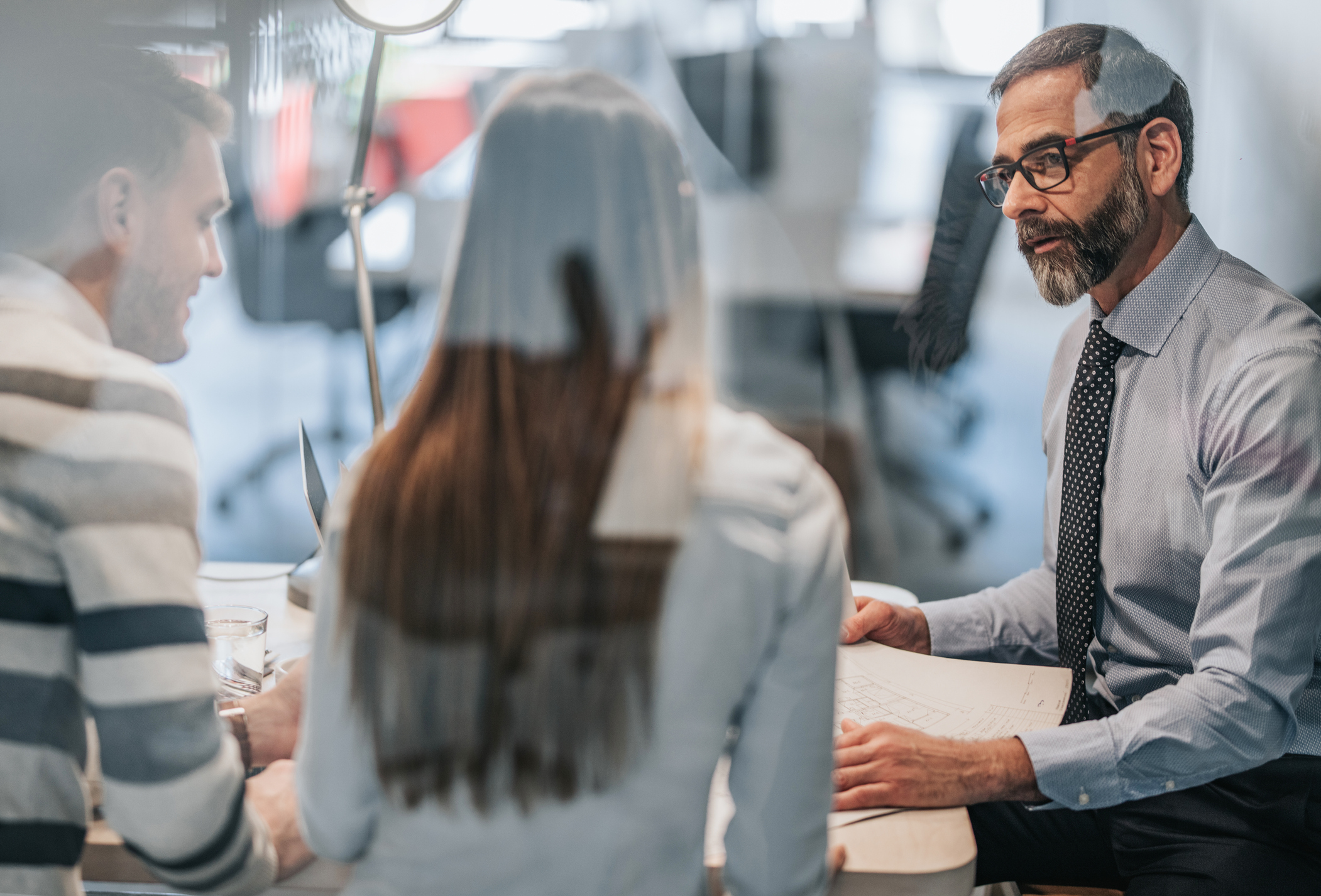 Drei Personen schauen in einen Vertrag
