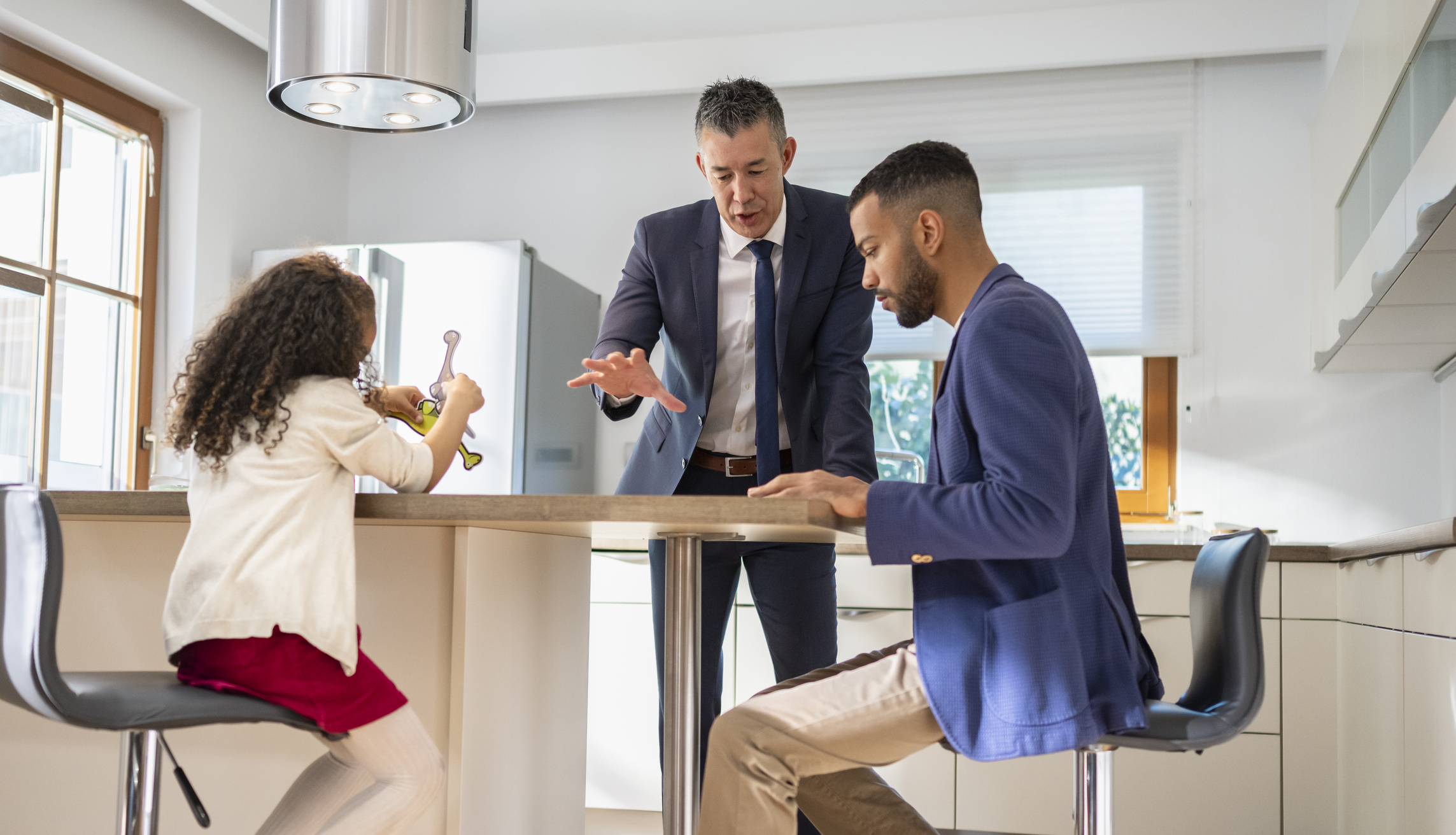 Berater erklärt einem Paar am Küchentisch Vertragsdetails zum Internetanbieter-Wechsel beim Umzug, während beide Unterlagen prüfen.