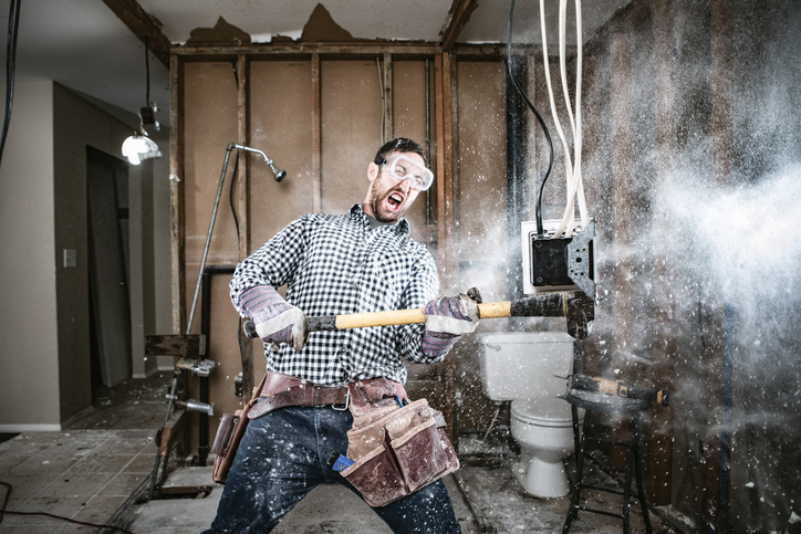 Man schlägt mit dem Vorschlaghammer Wand kaputt