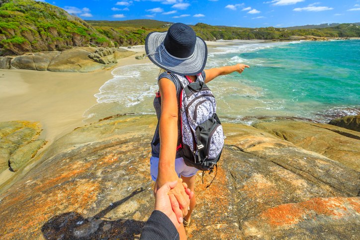 Auswandern nach Australien: Wissenswertes zum Umzug nach Down Under Junge Frau zeigt auf Strand und Meer in Australien