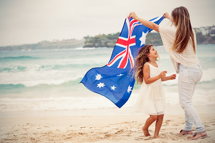 Auswandern nach Australien Frau und Tochter mit Australienflagge am Strand
