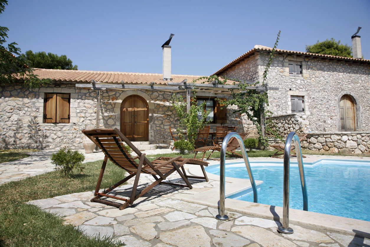 Vor einem alten steinernen Haus in Griechenland befinden sich Pool und Liegen