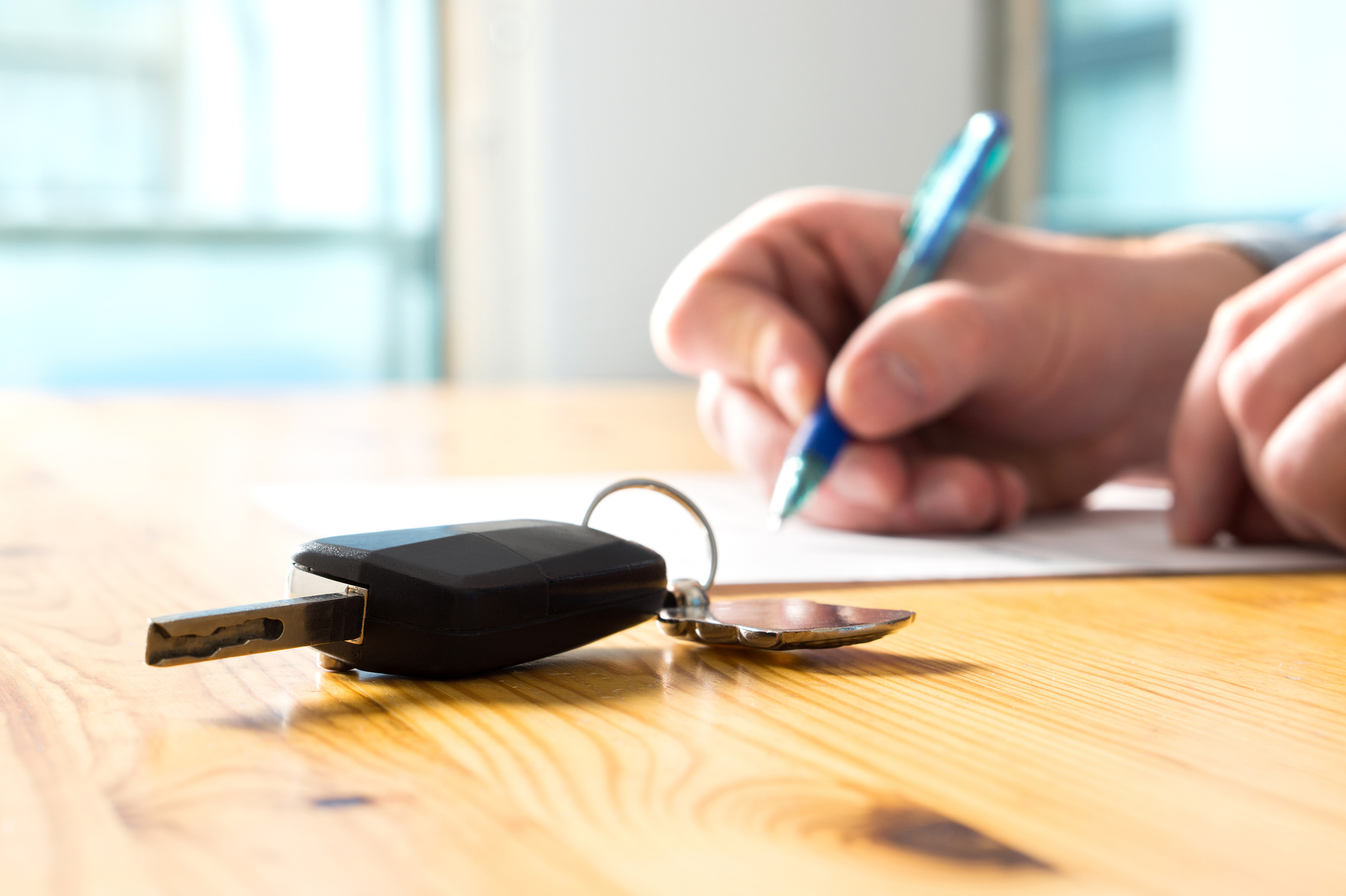 Auto privat verkaufen: Warum der Kaufvertrag so wichtig ist Hand mit Stift und Autoschlüssel unterschreibt einen Vertrag