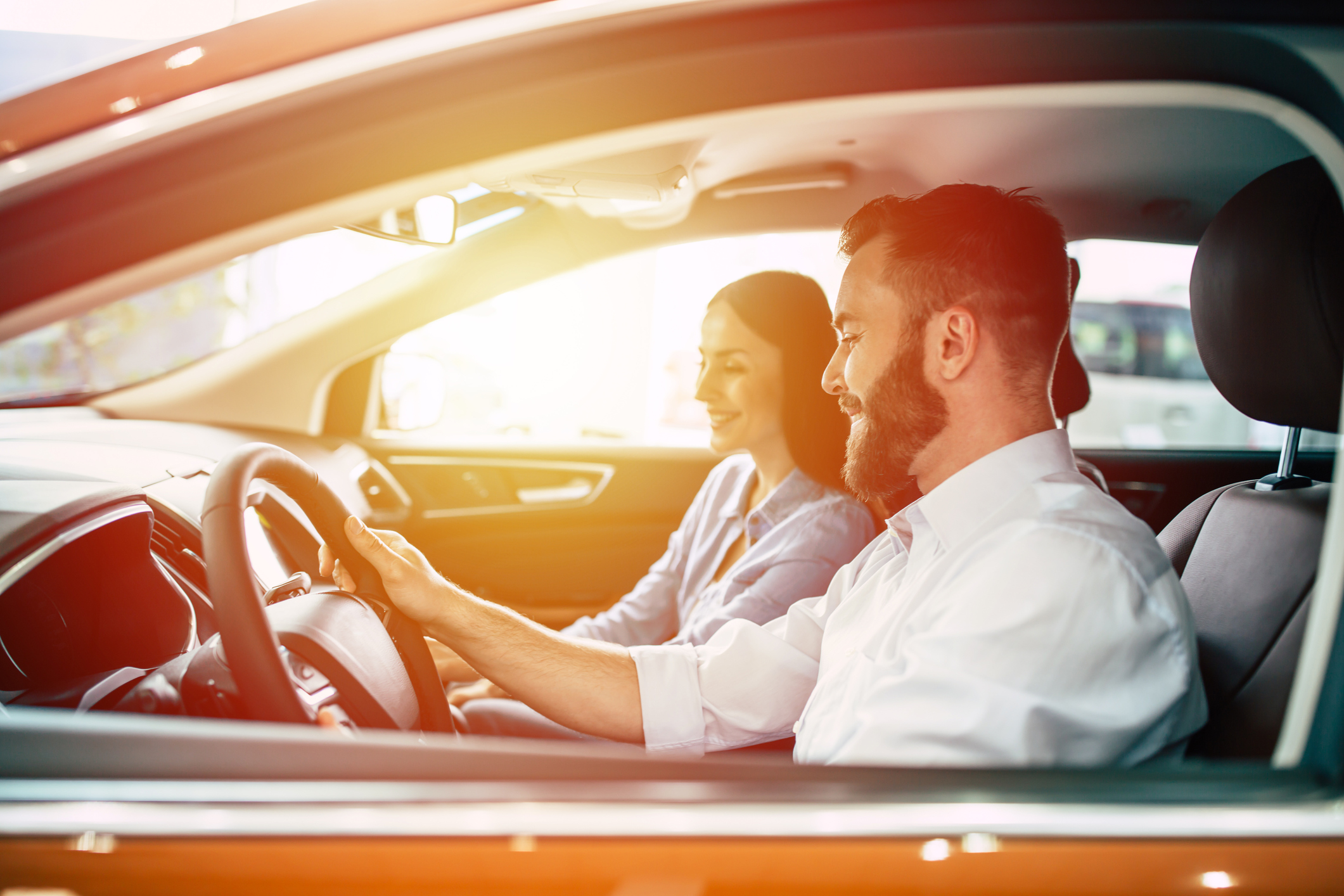 Auto verkaufen: Schnell und sicher von privat Junger Mann und junge Frau lächelnd im Auto bei einer Probefahrt