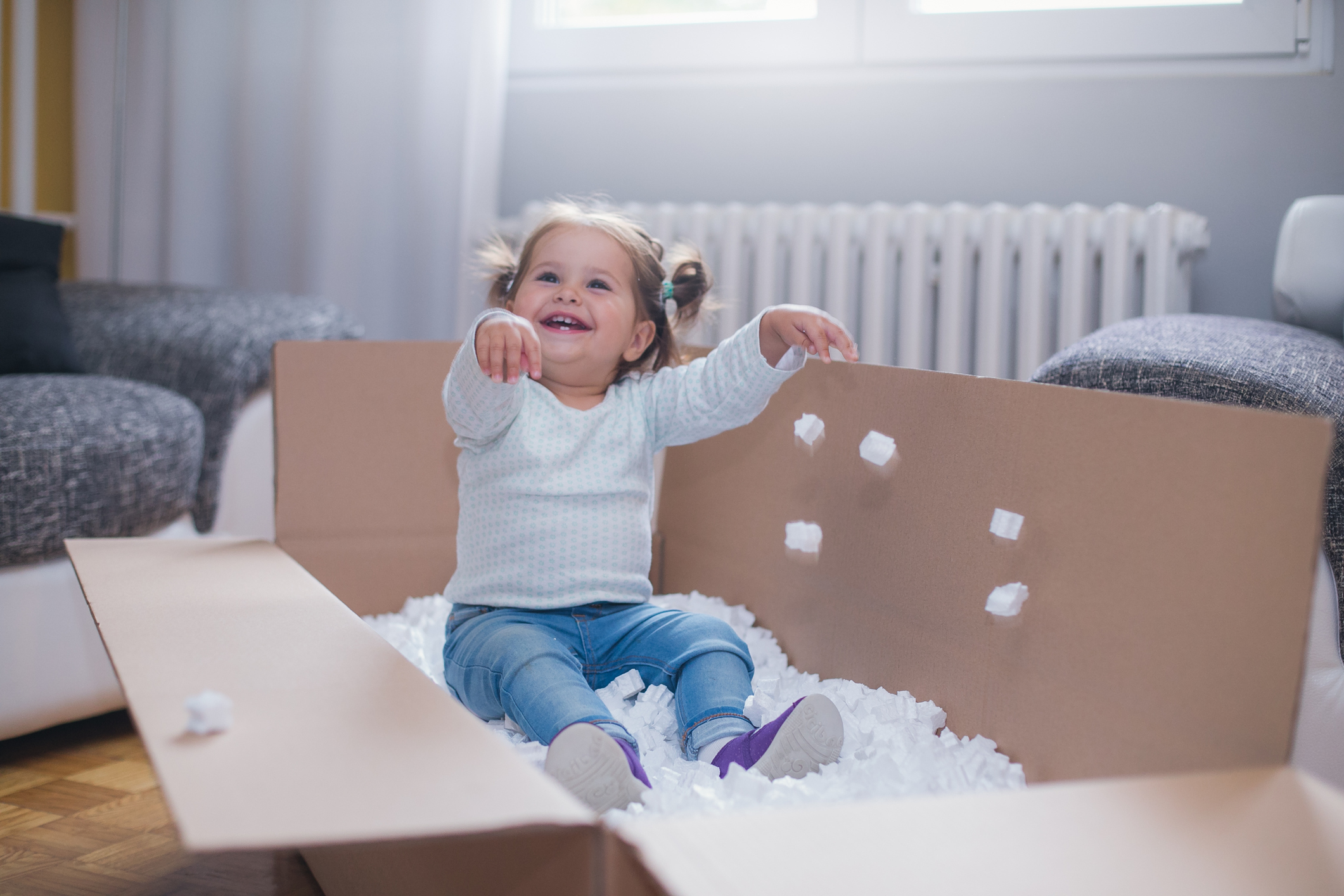 Umzugscheckliste 1 bis 3 Monate vor dem Umzug Kleinkind spielt mit Verpackungsmaterial in Umzugskiste